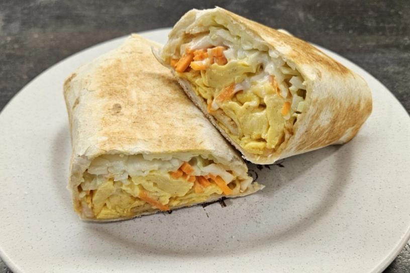 A halved tortilla roll with filling, served on a plate.