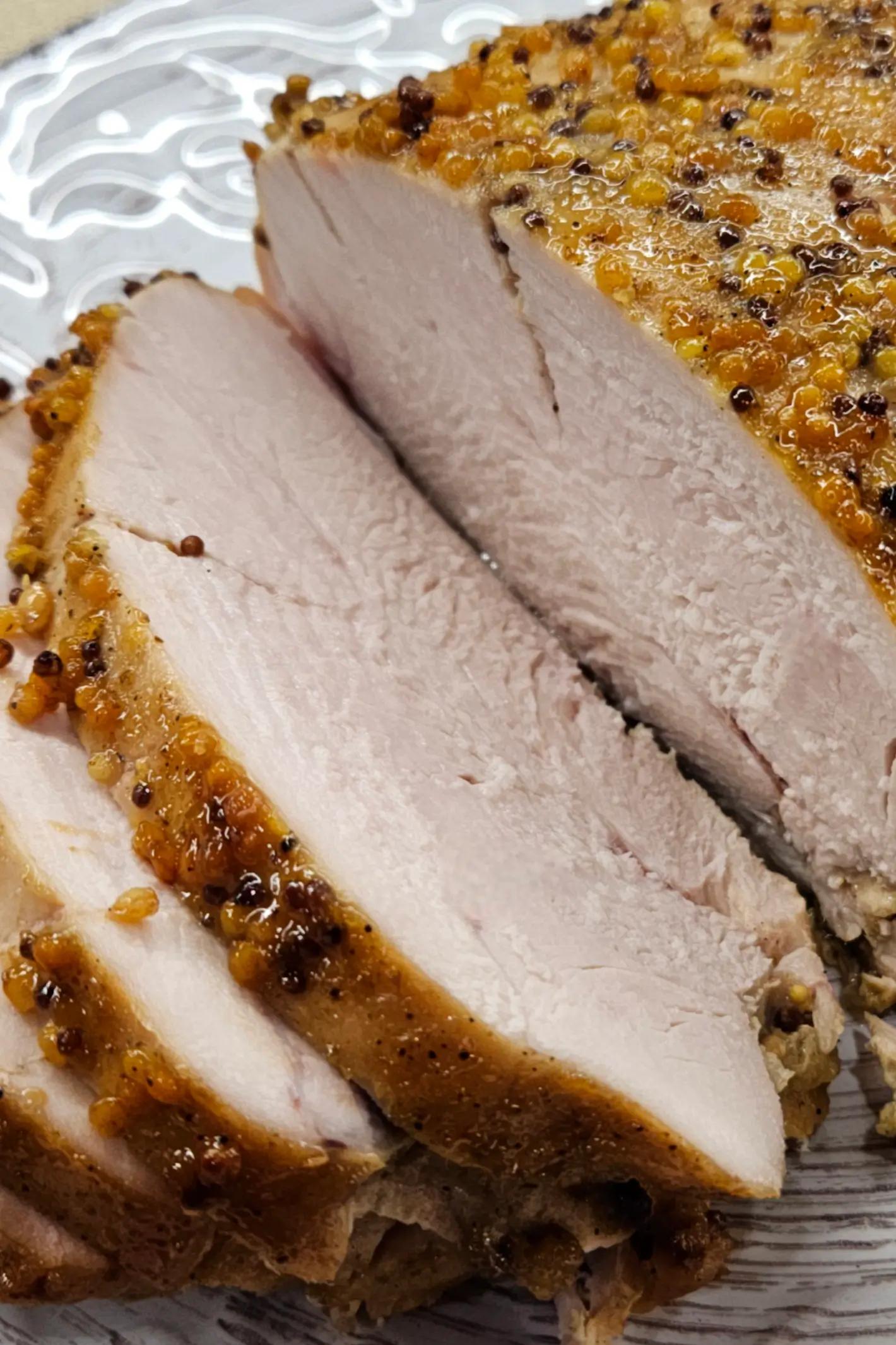 Нарізане філе індички з медово-гірчичною скоринкою та спеціями на декоративній тарілці. М’ясо світле й соковите всередині.