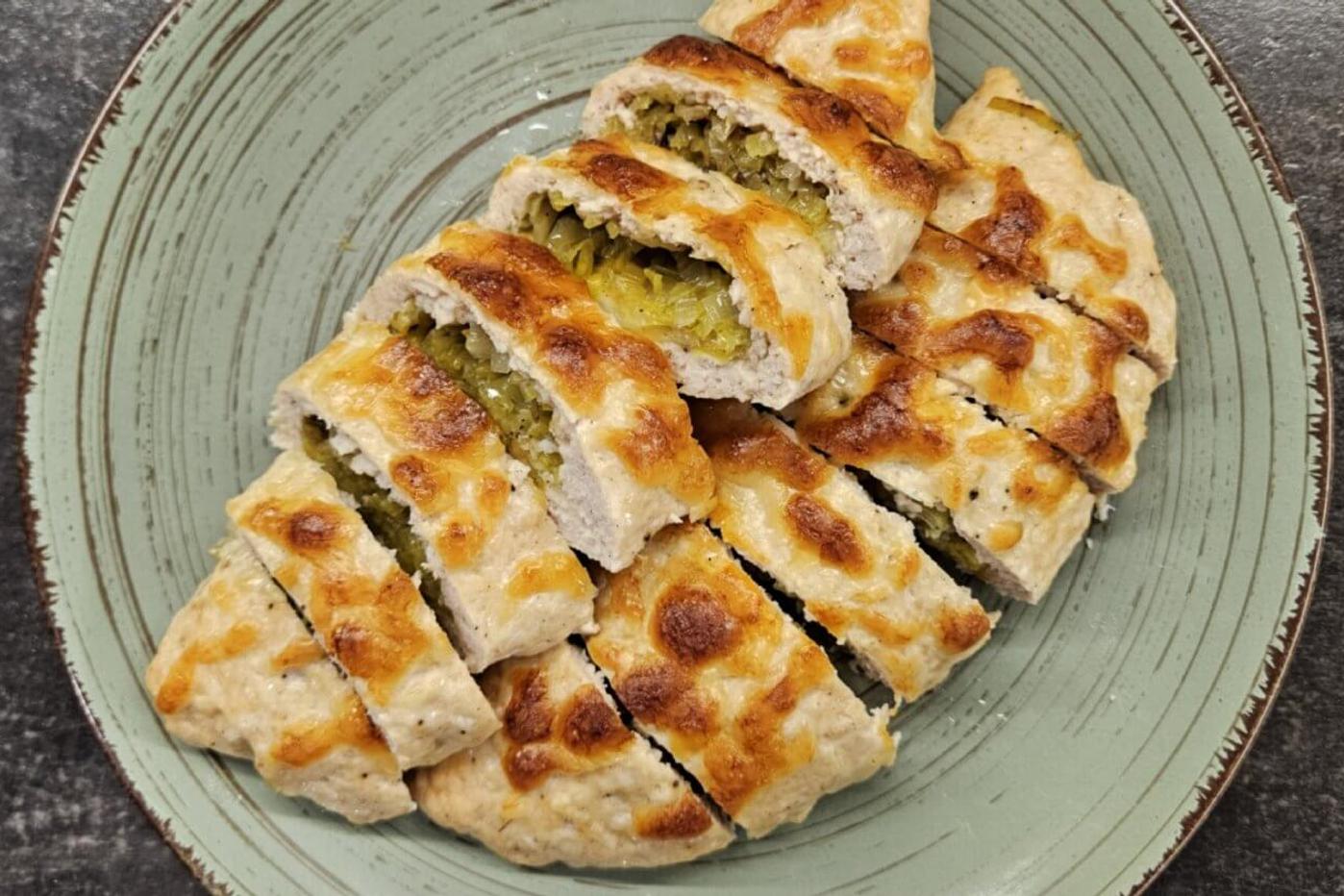 Chicken stuffed with mozzarella and leek, beautifully arranged on a green plate.