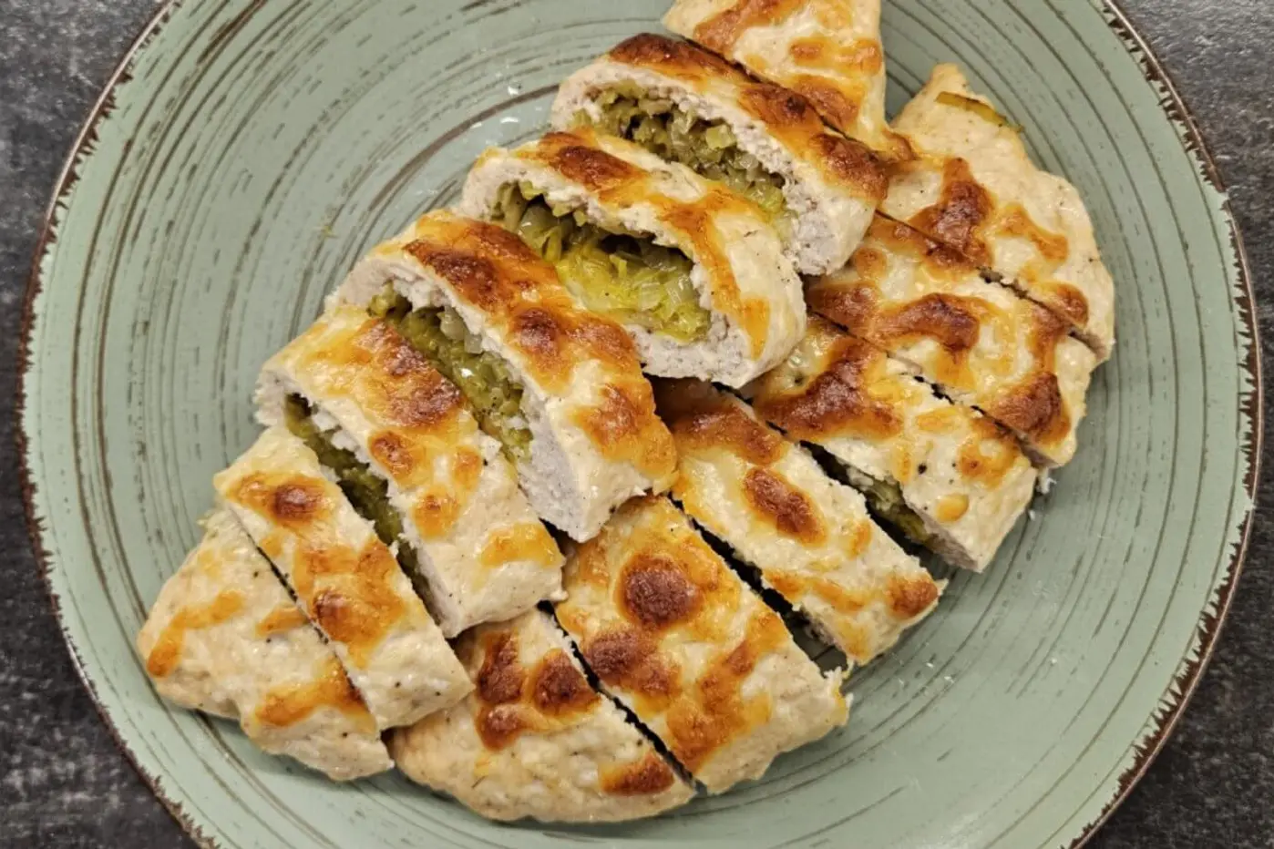 Chicken stuffed with mozzarella and leek, beautifully arranged on a green plate.