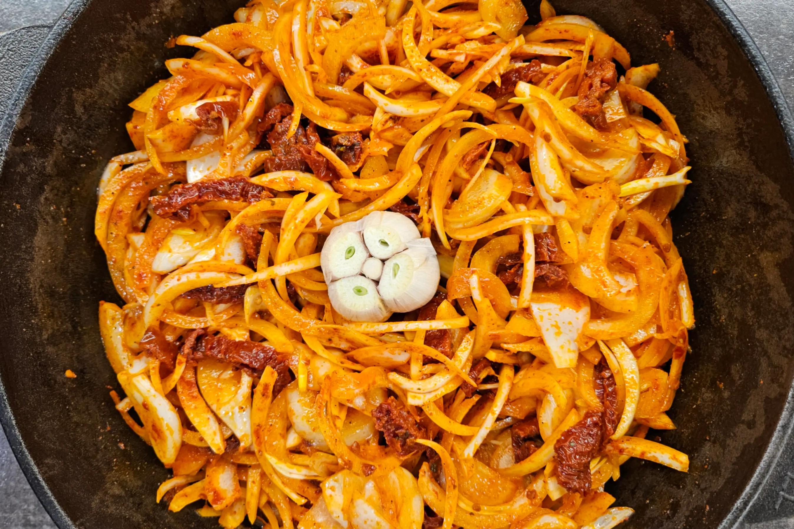 Головка часнику з зрізаною верхівкою, викладена посеред цибулі у формі.