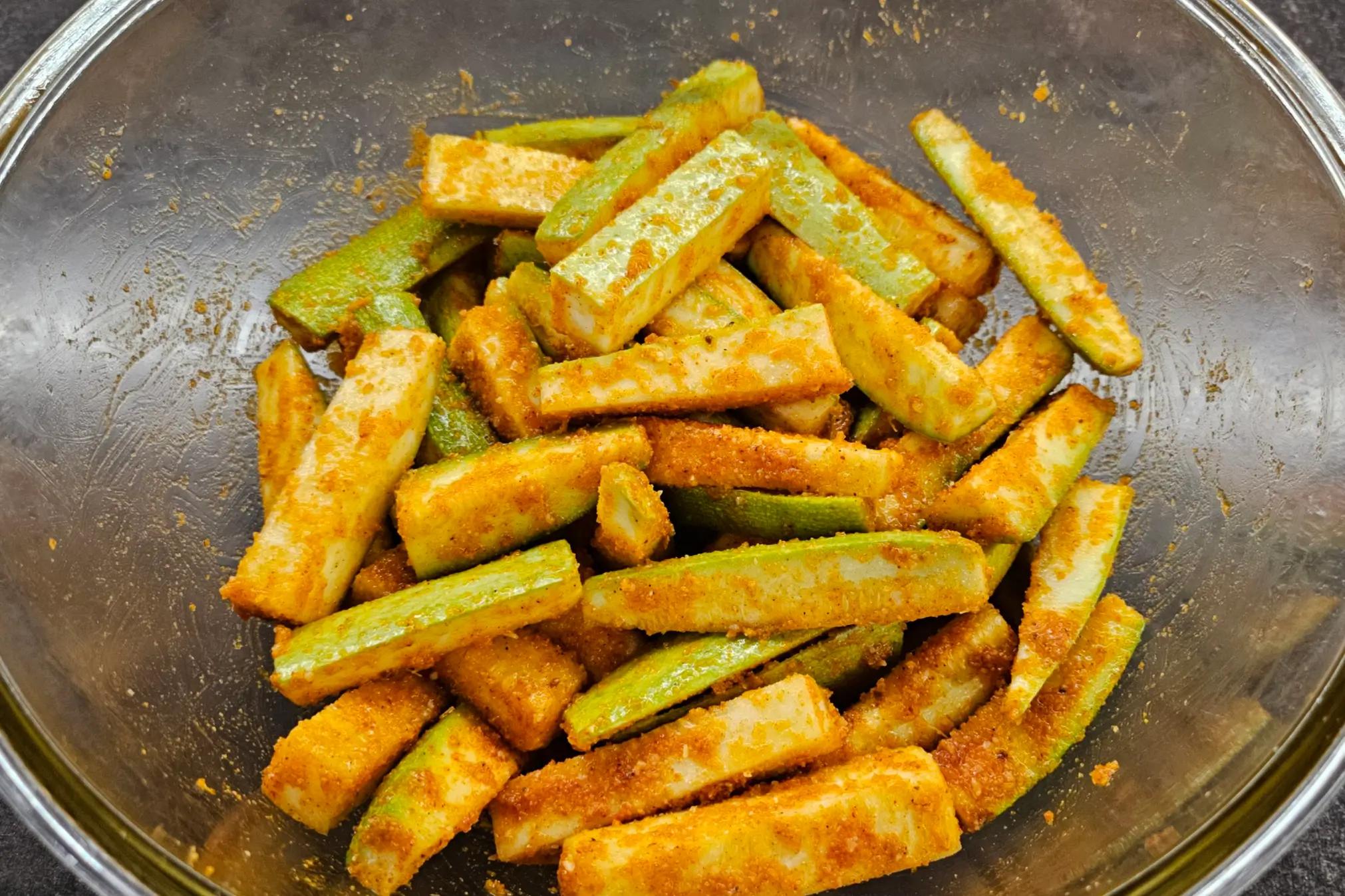 Coated zucchini sticks covered with seasoned breadcrumbs and grated cheese.