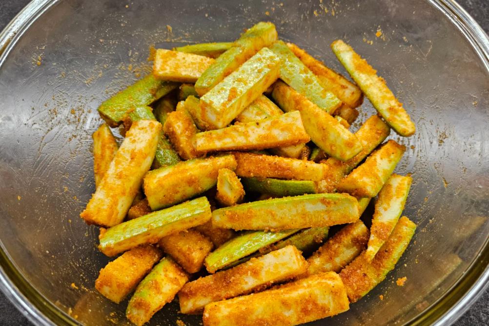 Coated zucchini sticks covered with seasoned breadcrumbs and grated cheese.
