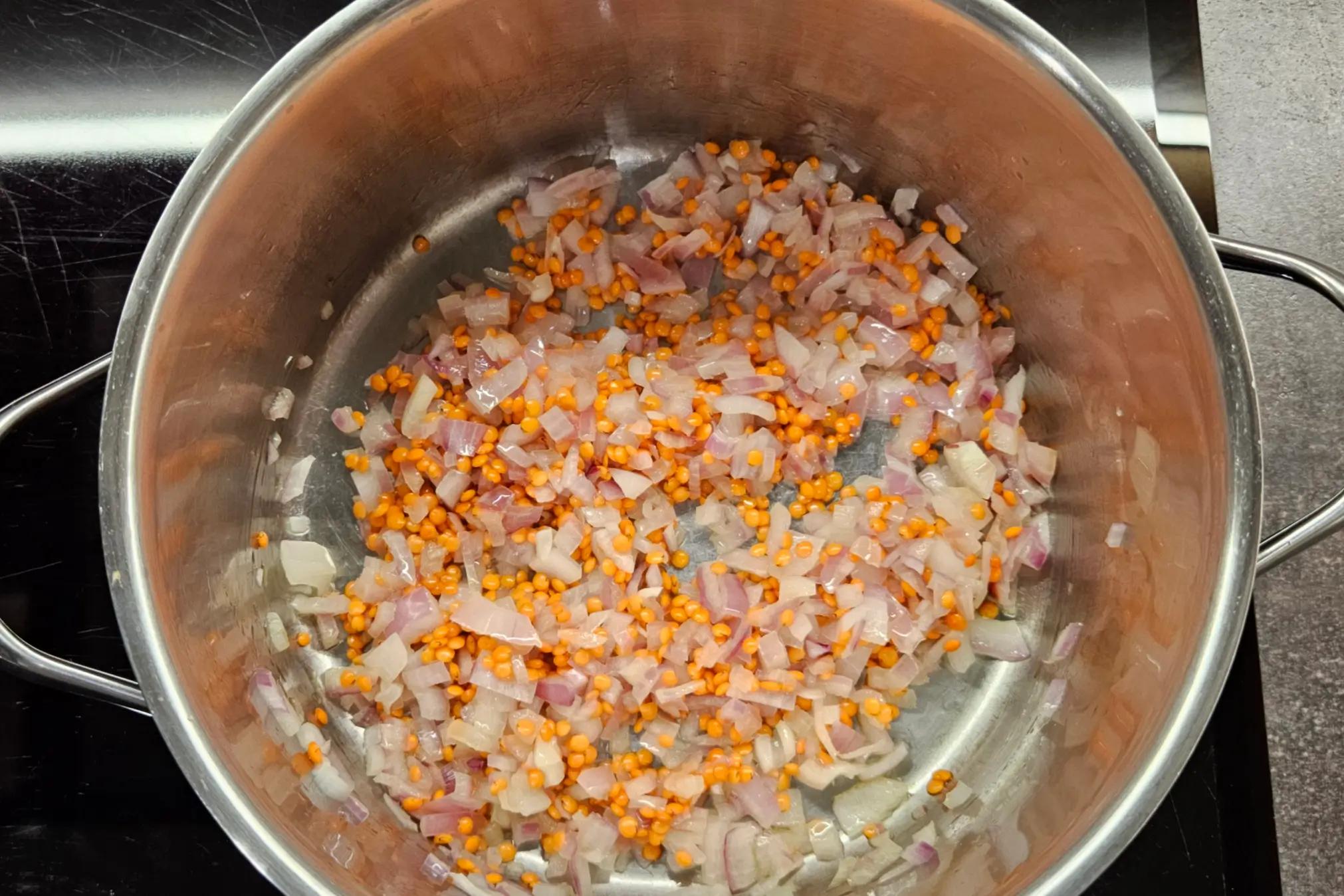 Rinsed red lentils added to the pot with the sautéed red onions and toasted spices.