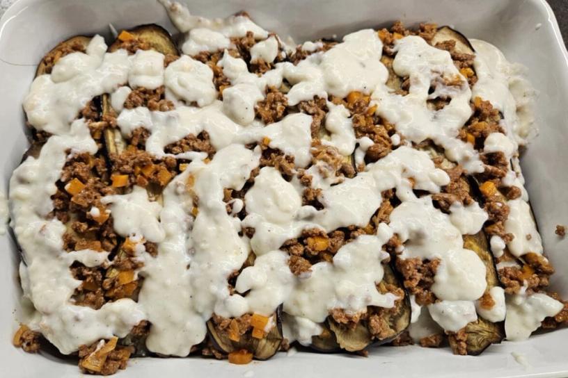 A lasagna layer covered with béchamel sauce in a baking dish.