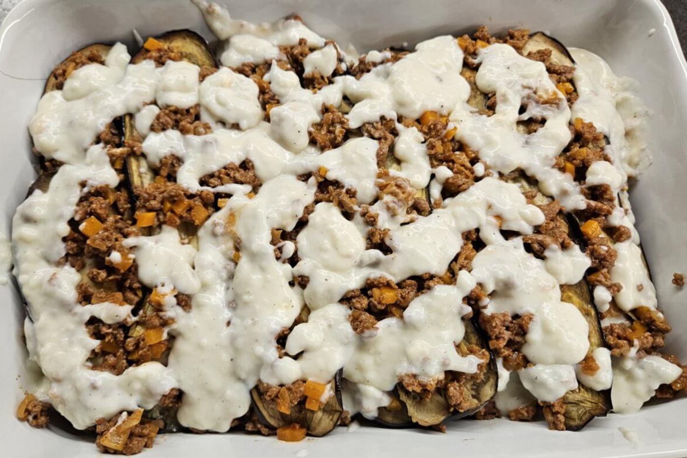 A lasagna layer covered with béchamel sauce in a baking dish.