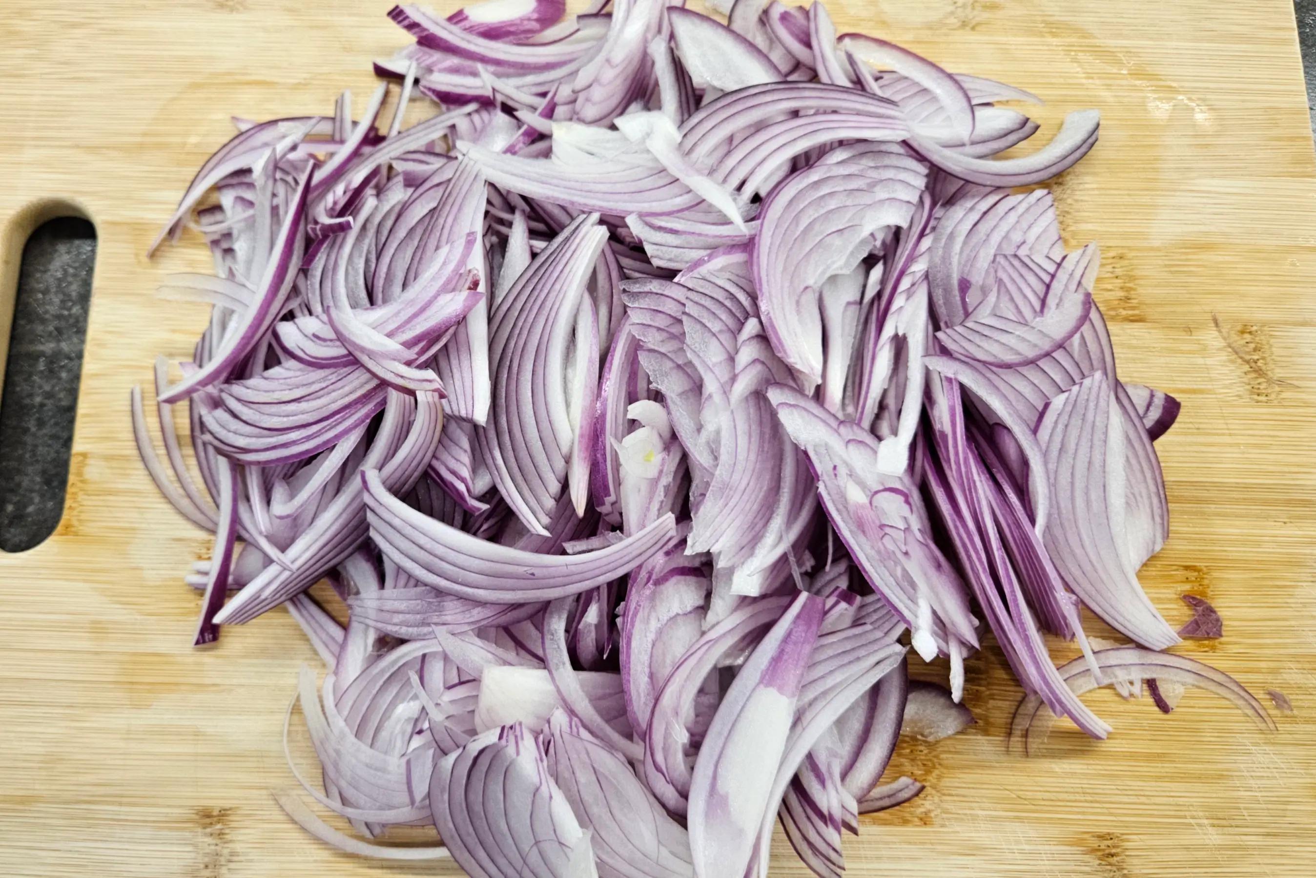Нарізана півкільцями червона цибуля для маринування.