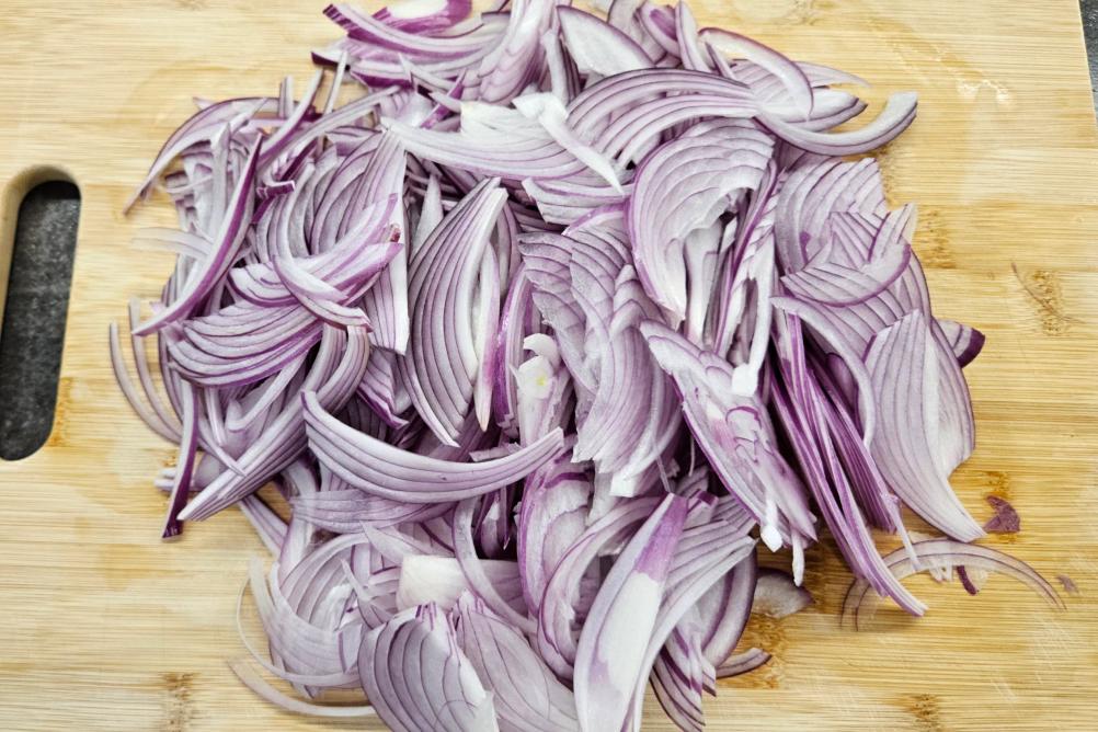 Нарізана півкільцями червона цибуля для маринування.