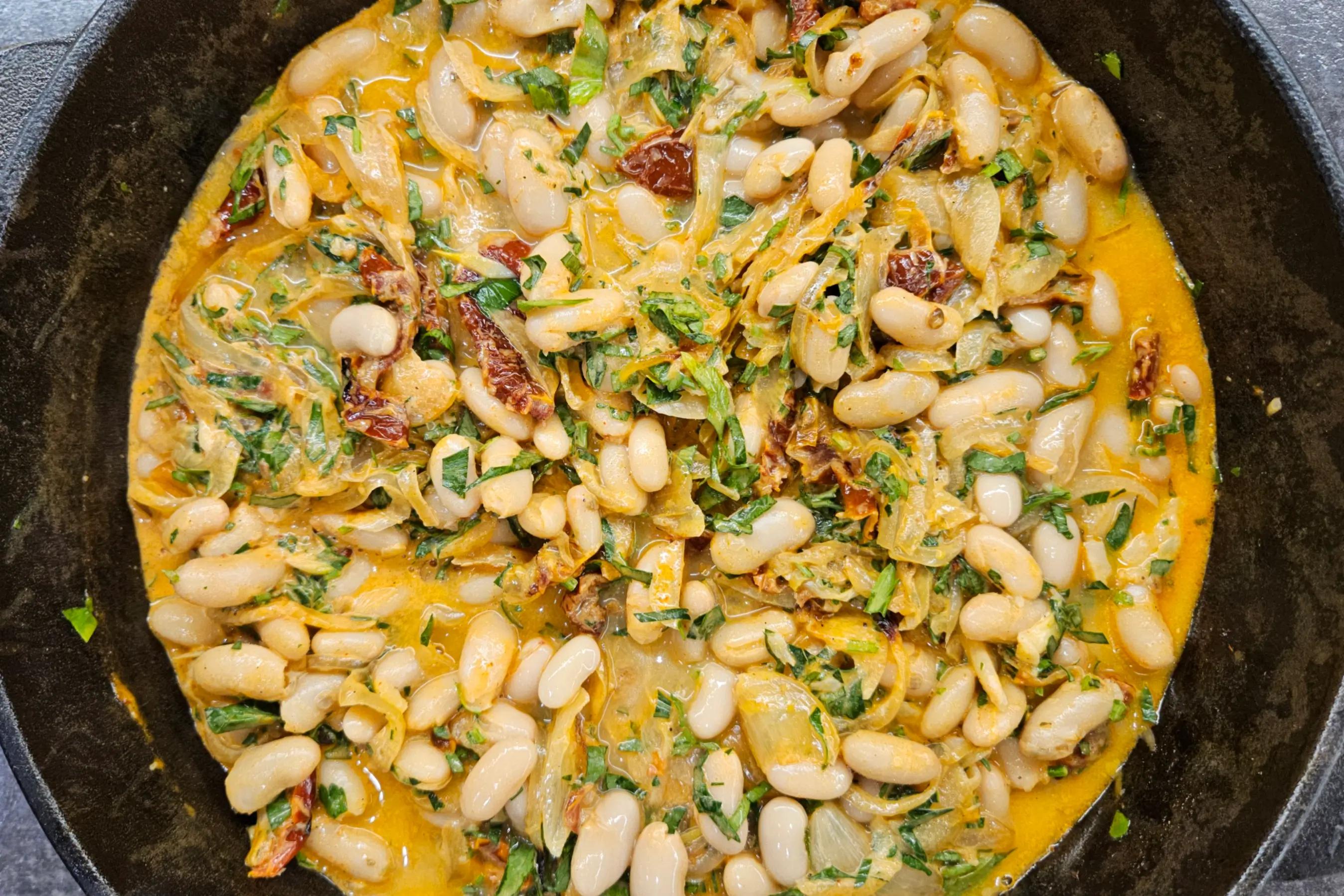 Додавання квасолі, вершків і запеченого часнику до цибулі у формі та перемішування.