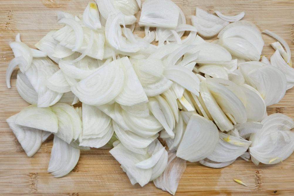 Нарізана півкільцями ріпчаста цибуля на обробній дошці.