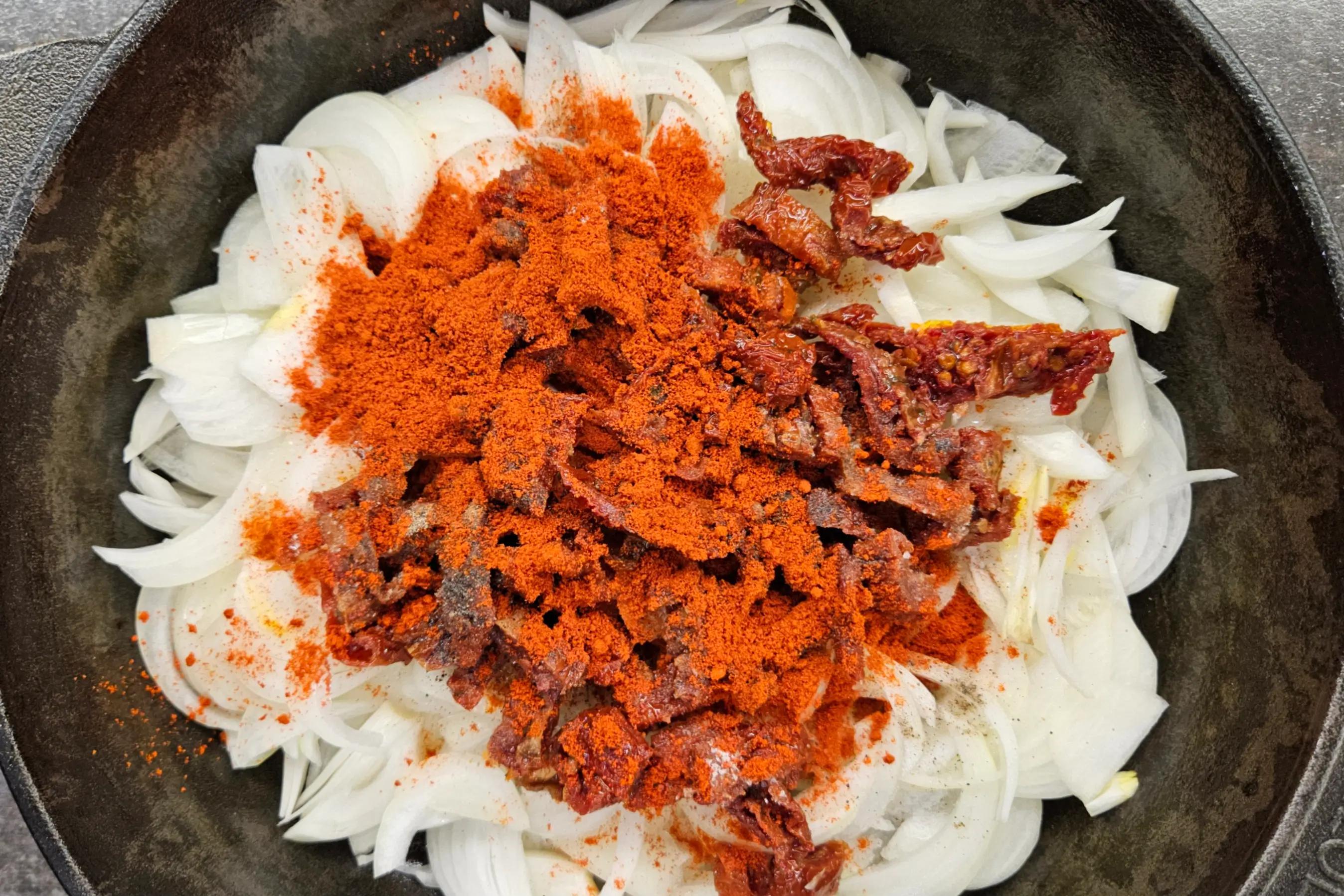 Цибуля та в’ялені томати зі спеціями, у формі для запікання.