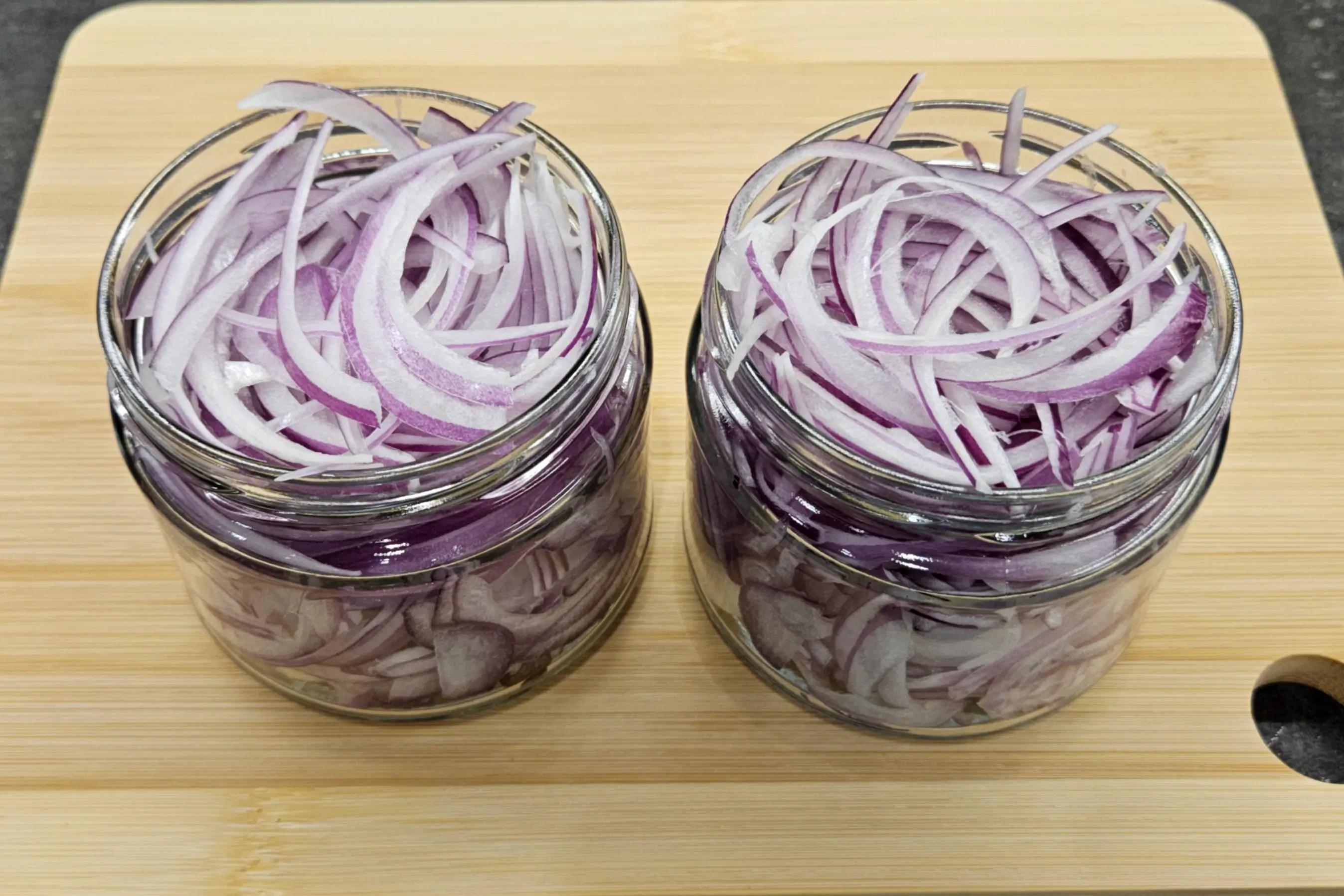 Банка щільно заповнена нарізаною червоною цибулею.