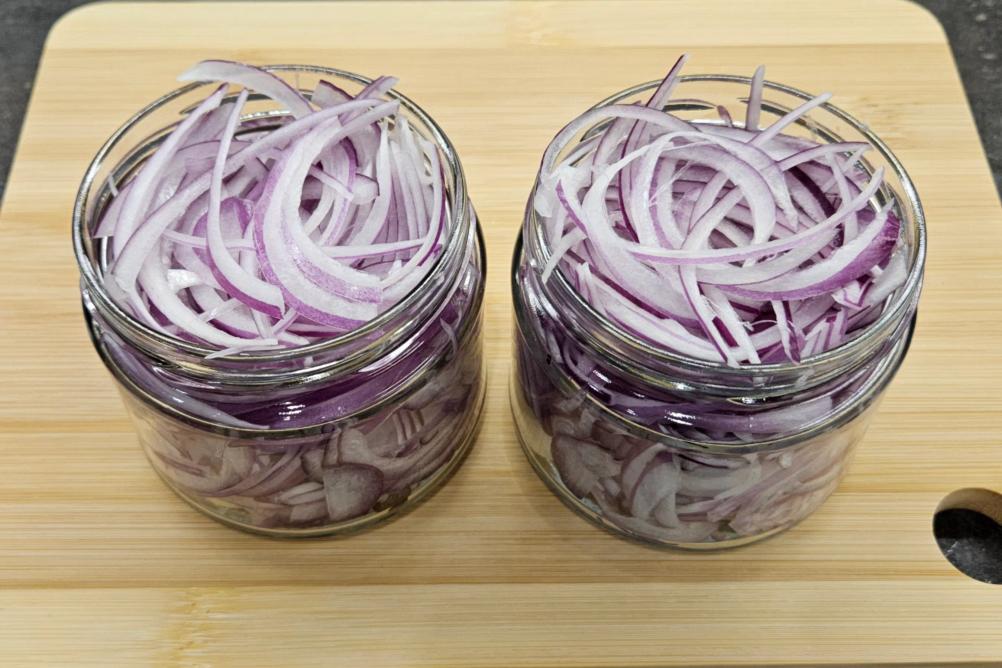 Банка щільно заповнена нарізаною червоною цибулею.