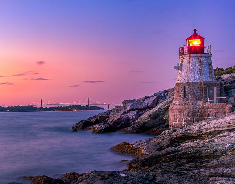 The beautiful Castle Hill Lighthouse in Rhode Island at sunset against the magenta and blue skies