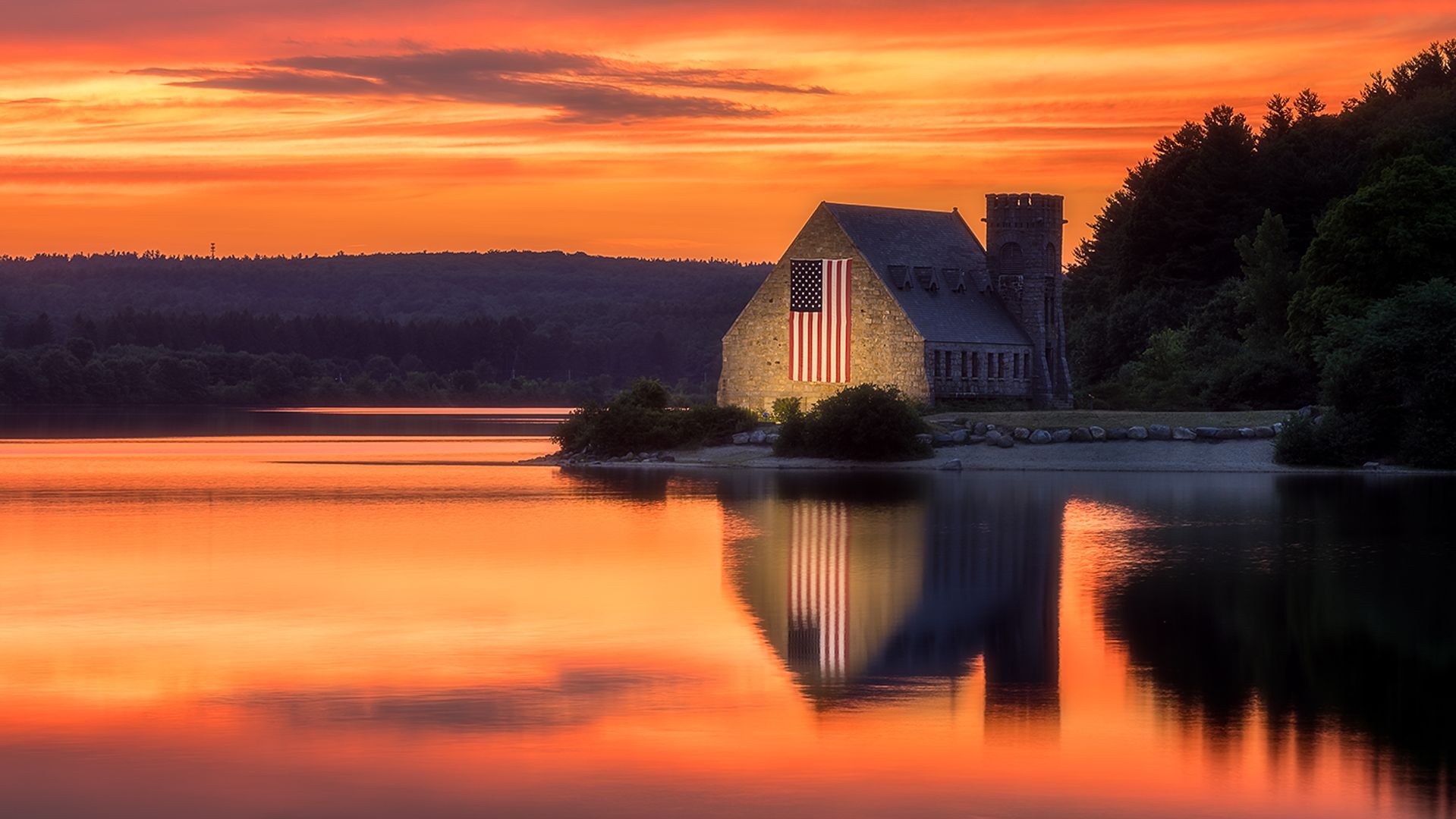 West Boylston MA Old Stone Church against a gold pink and magenta sunset