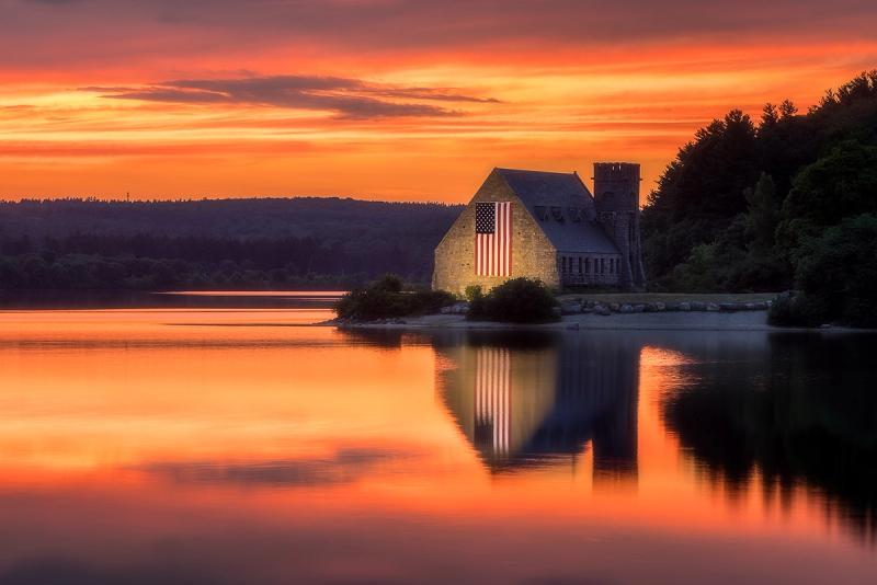 West Boylston MA Old Stone Church against a gold pink and magenta sunset