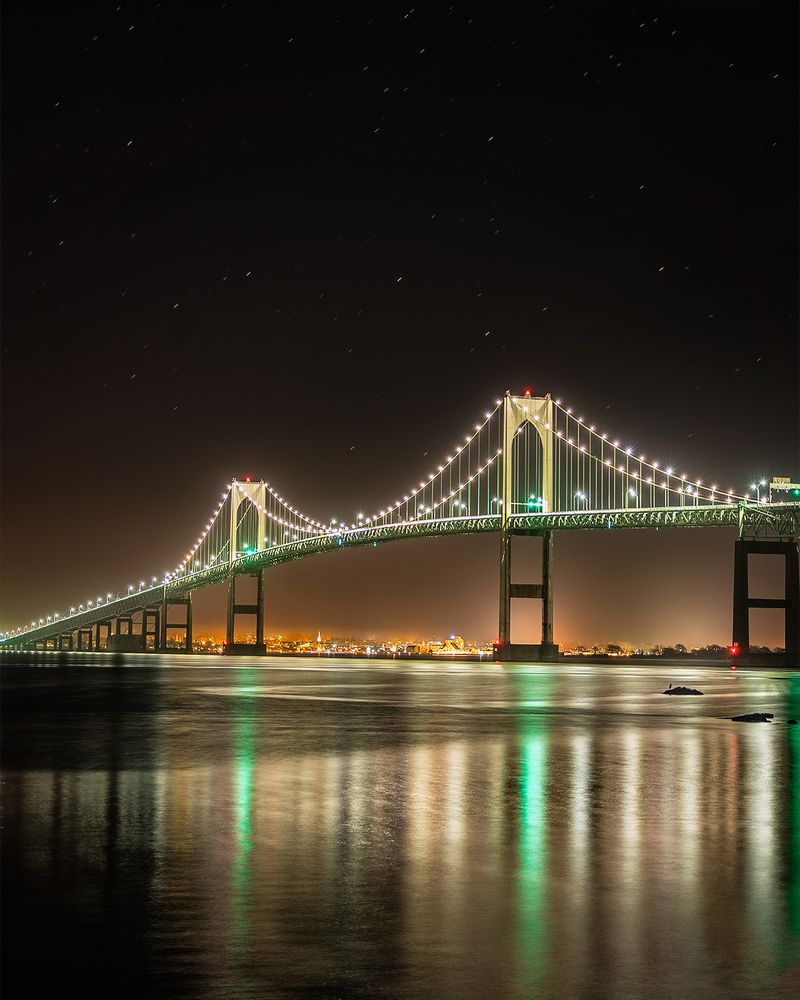 Gold colored Claroborne Pell Bridge at night