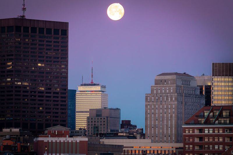 Early morning setting moon over the city of Boston with magenta and blue skies