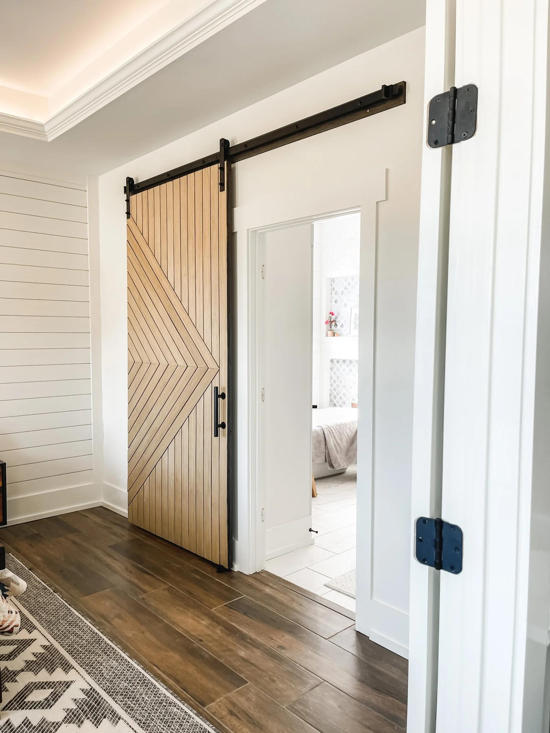 A finished modern slatted sliding barn door in a bathroom doorway