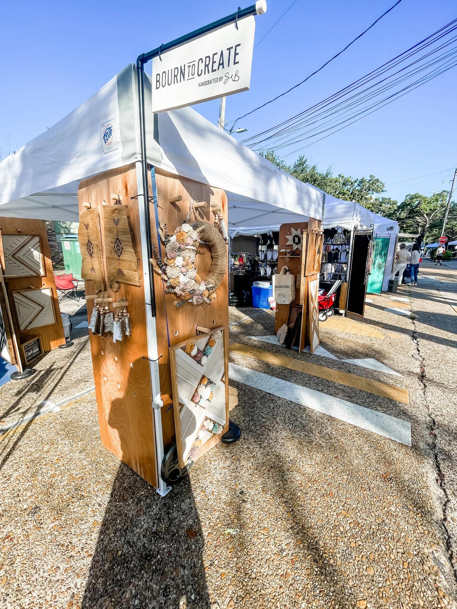 A handmade wood market booth display set up at an outdoor arts festival