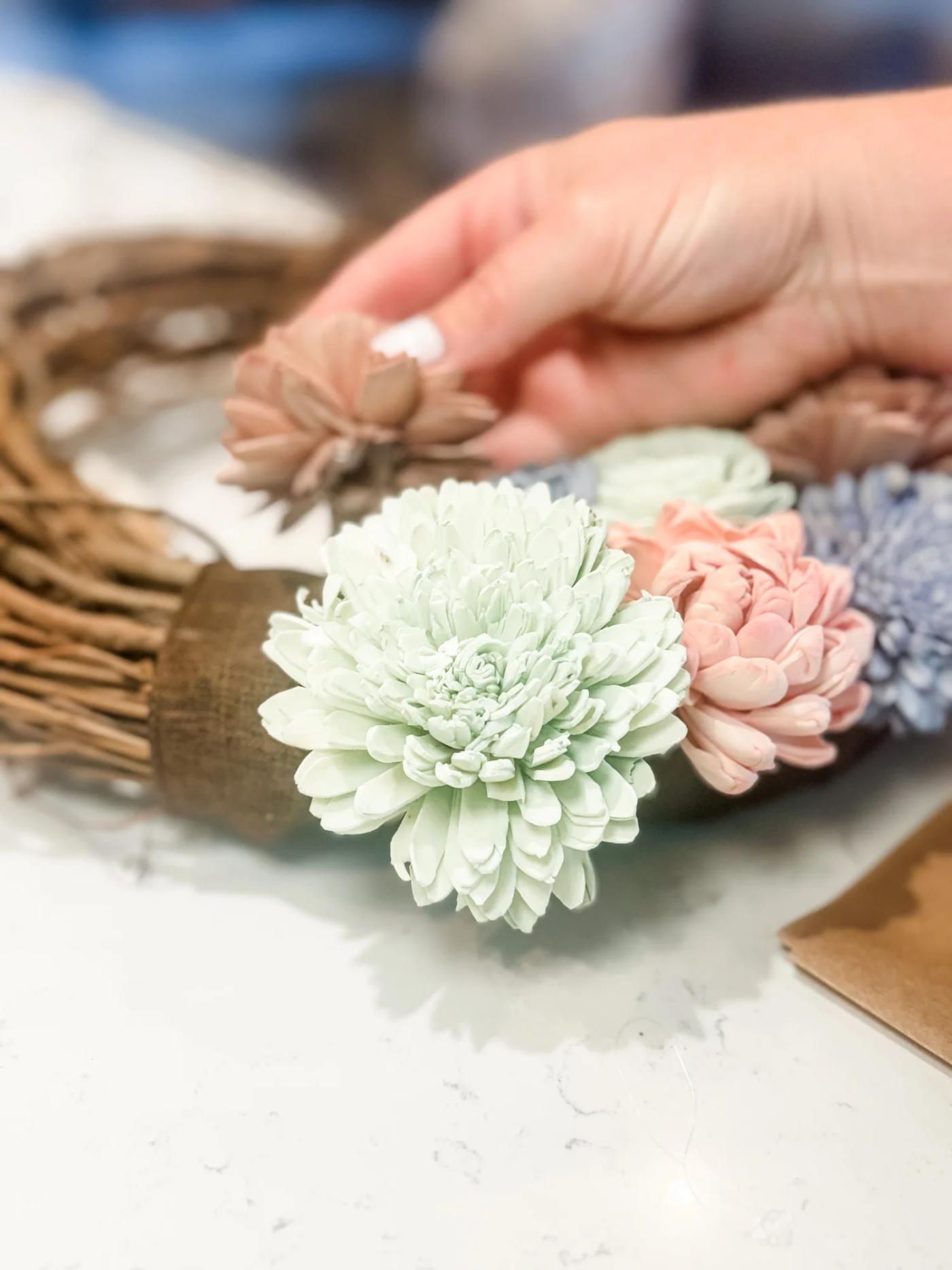 Gluing the dyed flowers onto the grapevine base