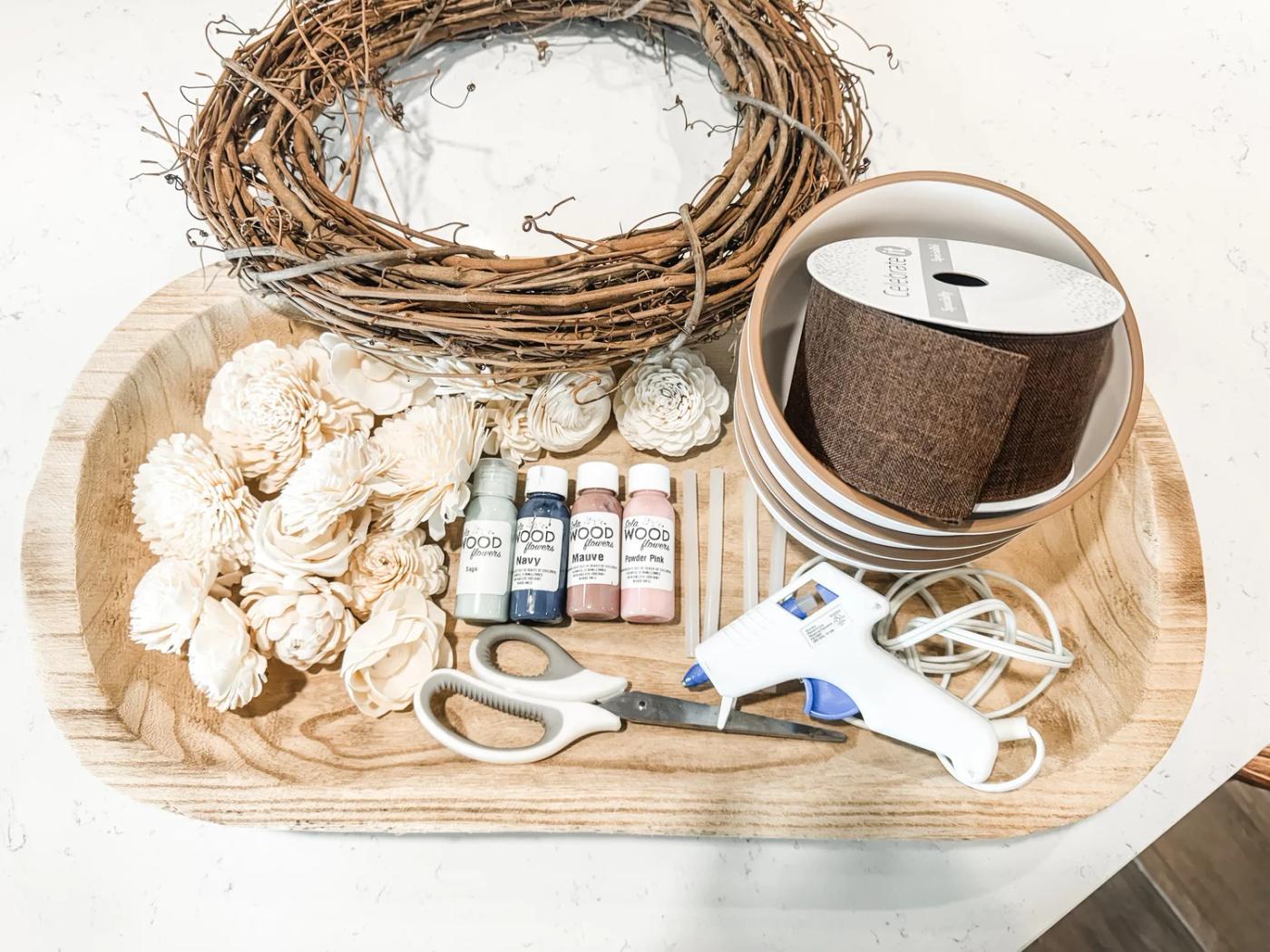 Everything laid out before I start — grapevine base, sola flowers, dye, ribbon, and the glue gun