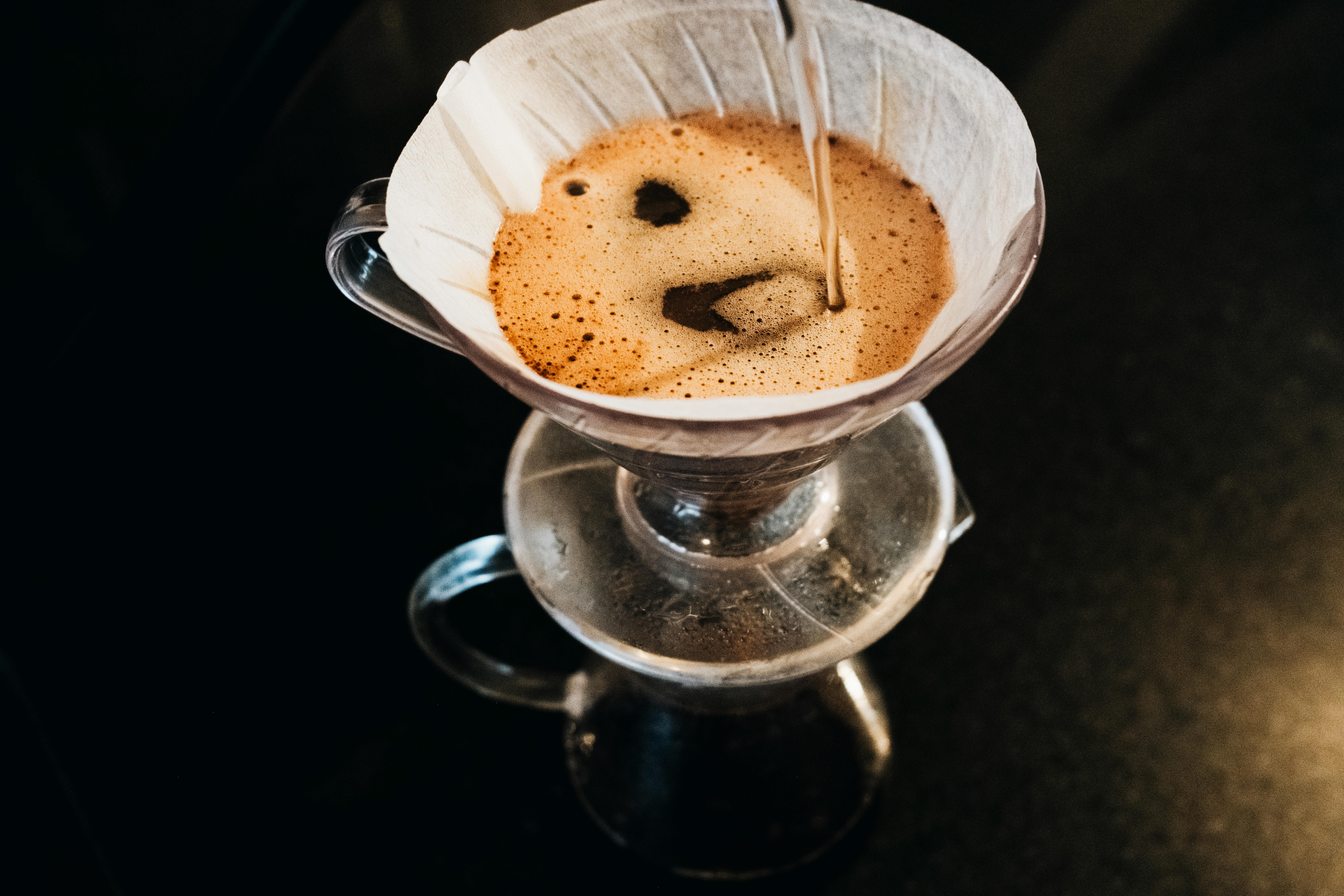 Overhead view of a glass carafe with condensation, reflecting on a dark surface.