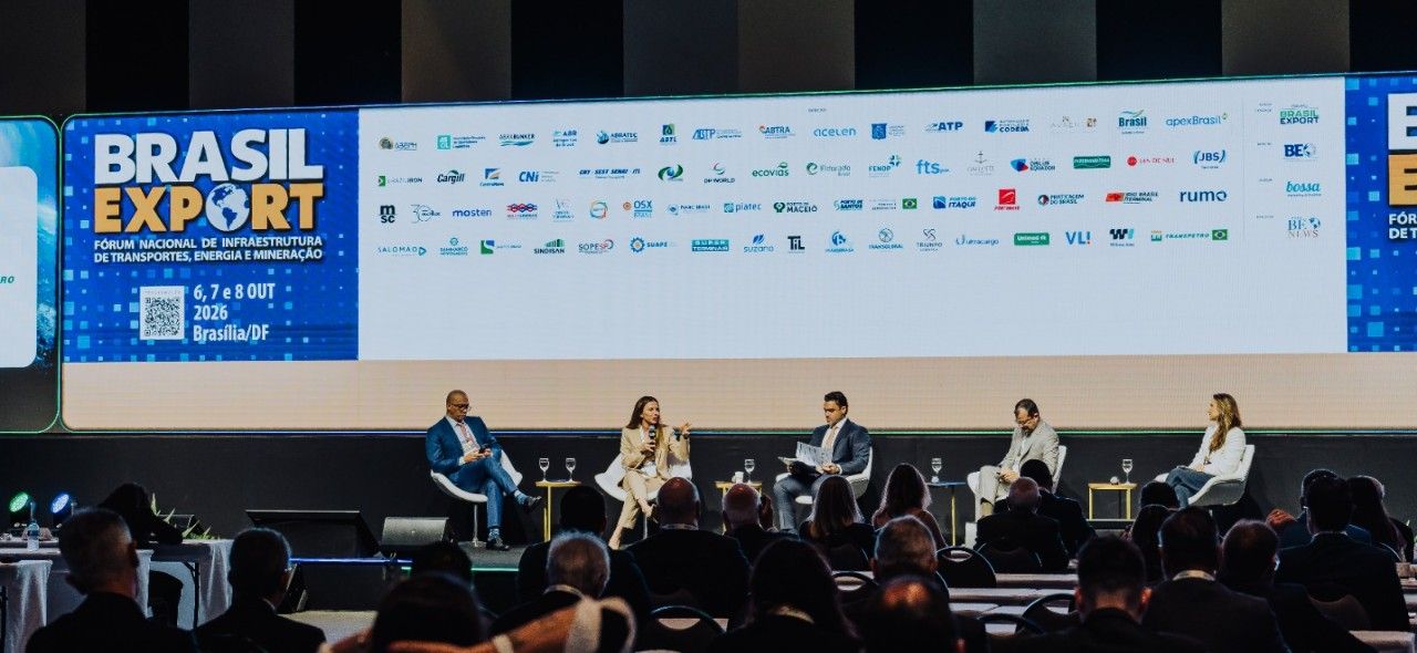 Cinco participantes sentados no palco do painel InfraESG do Fórum Brasil Export 2026, diante do telão do evento em Brasília