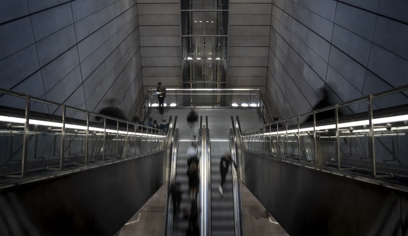 People on escalators in a modern underground station.