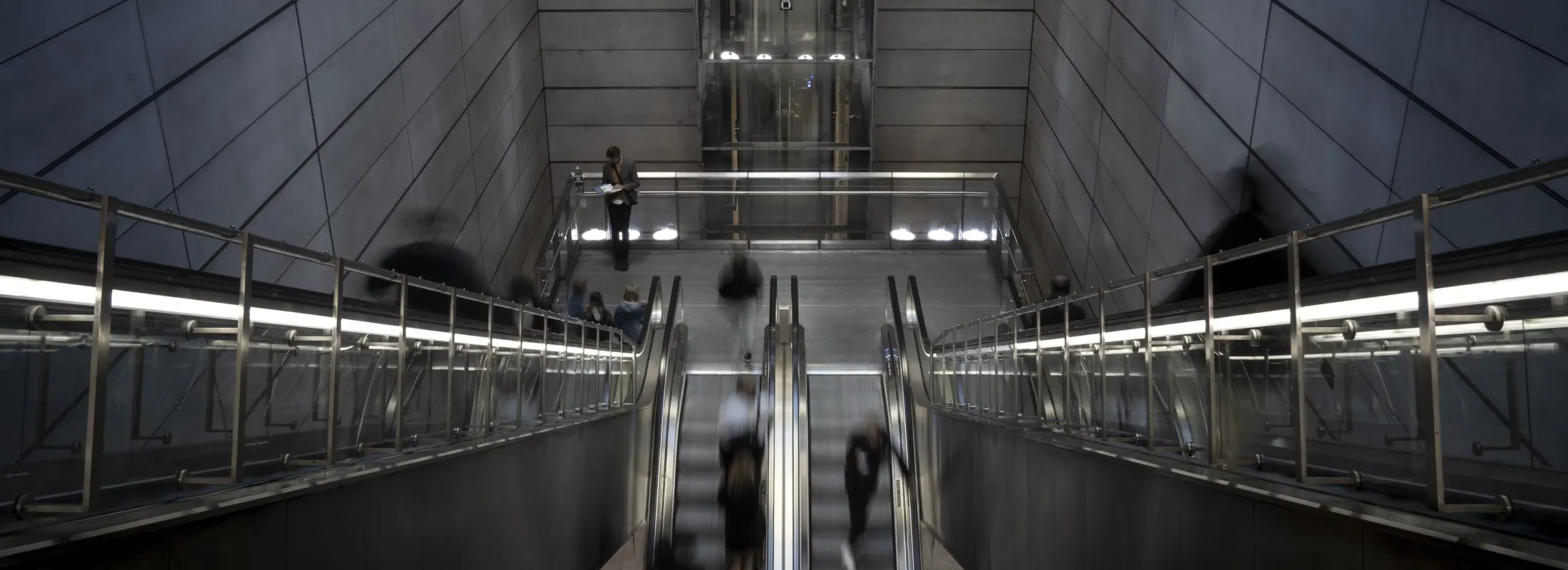 People on escalators in a modern underground station.