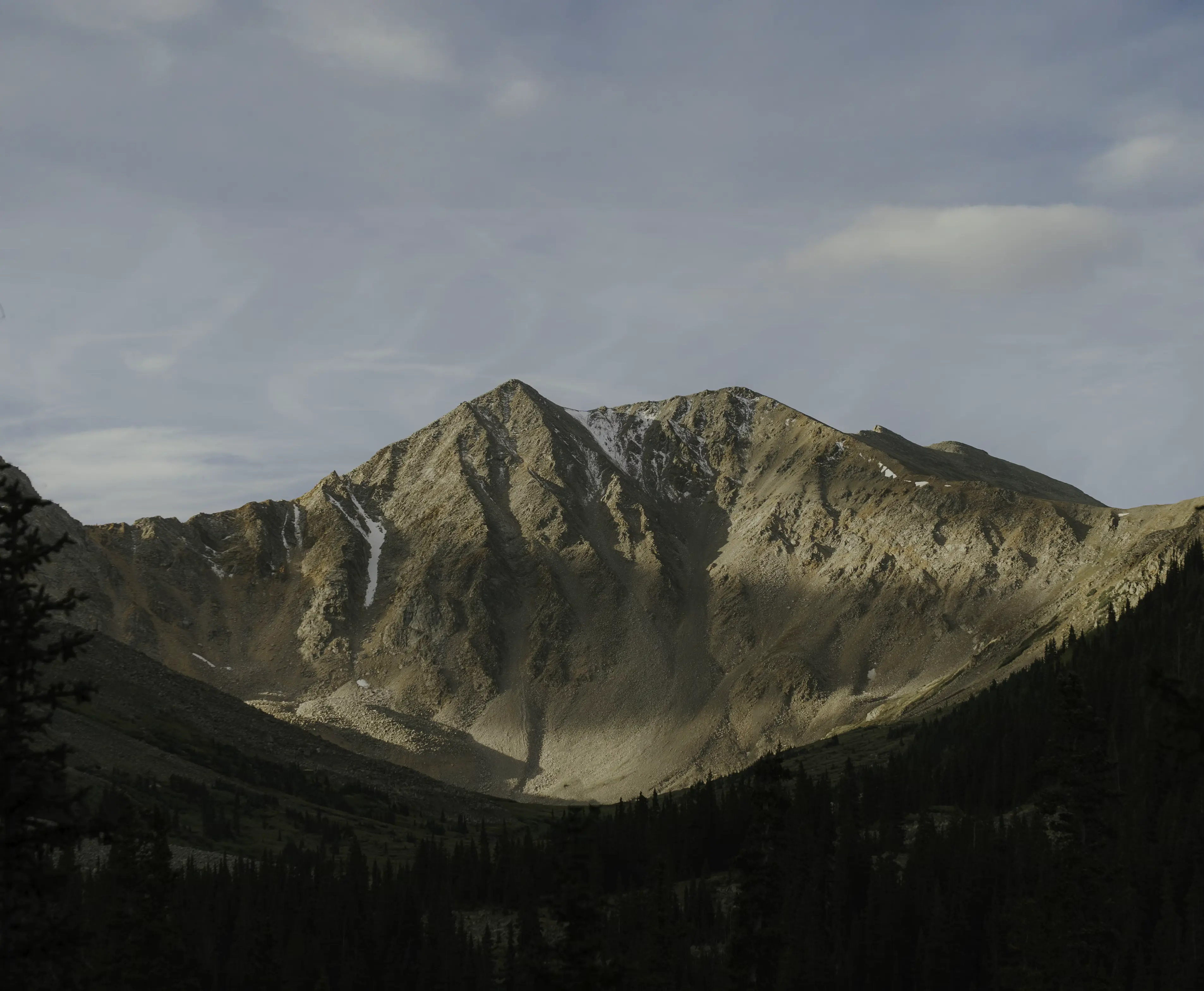 Rocky mountain peak under a cloudy sky.