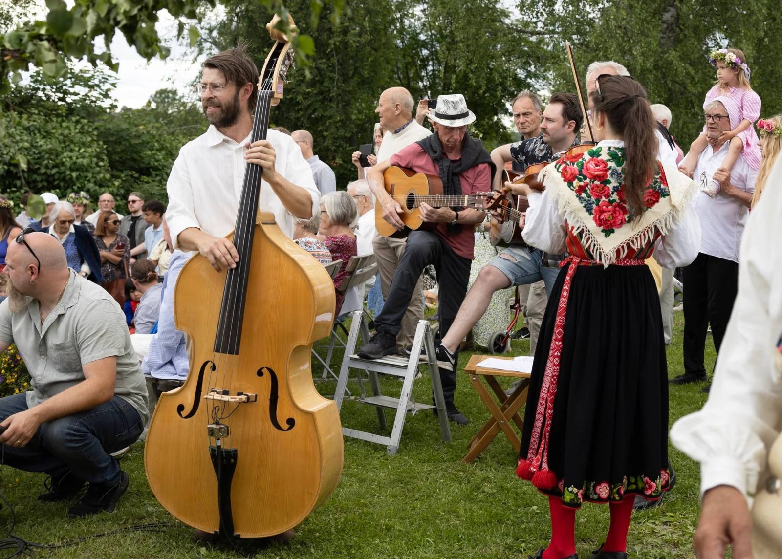 Spelmän med bas och gitarr framför en sittande publik på en gräsmatta.