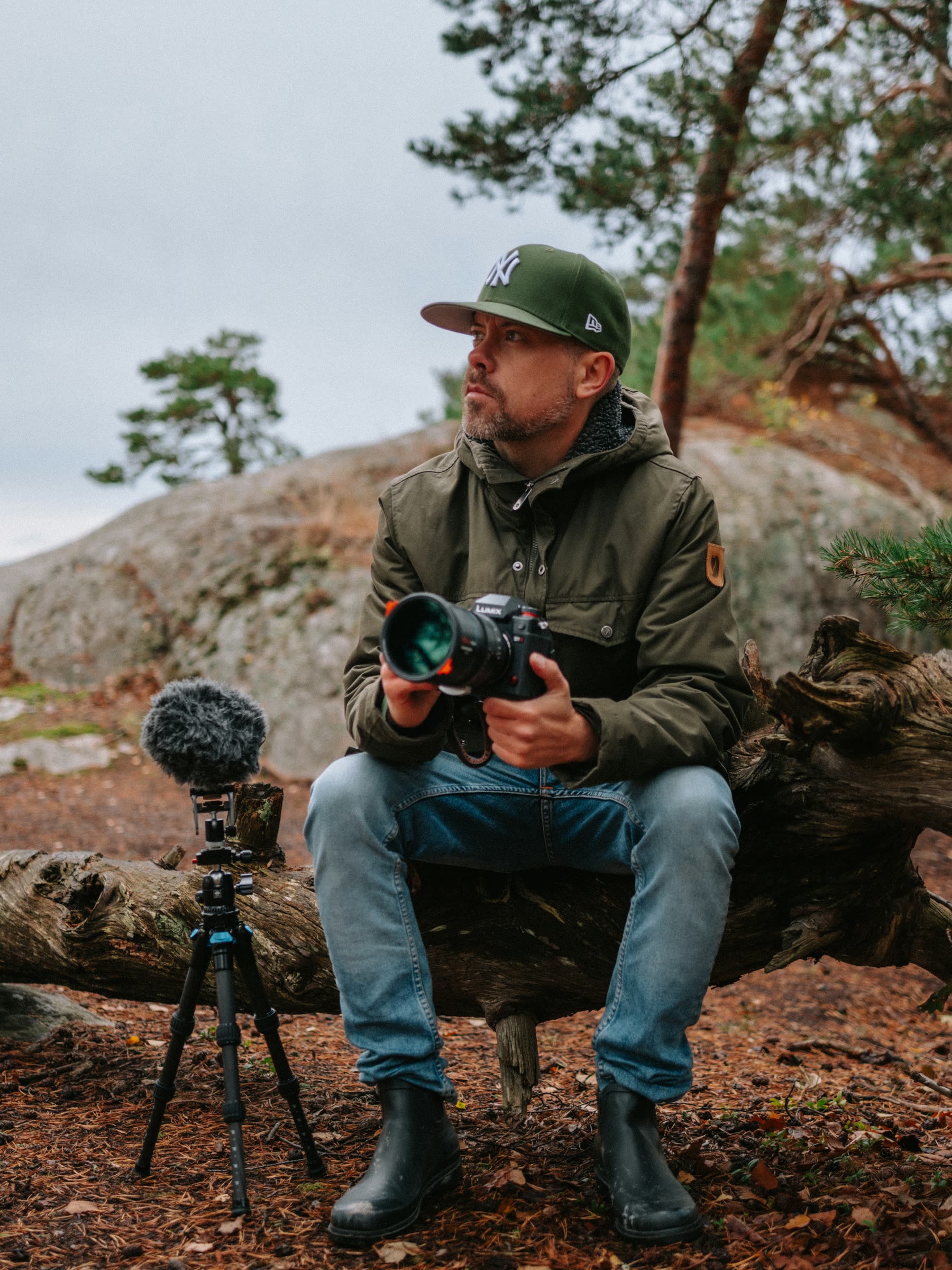 Johan Norlund sitting in a pine forest with his camera and field-recording microphone