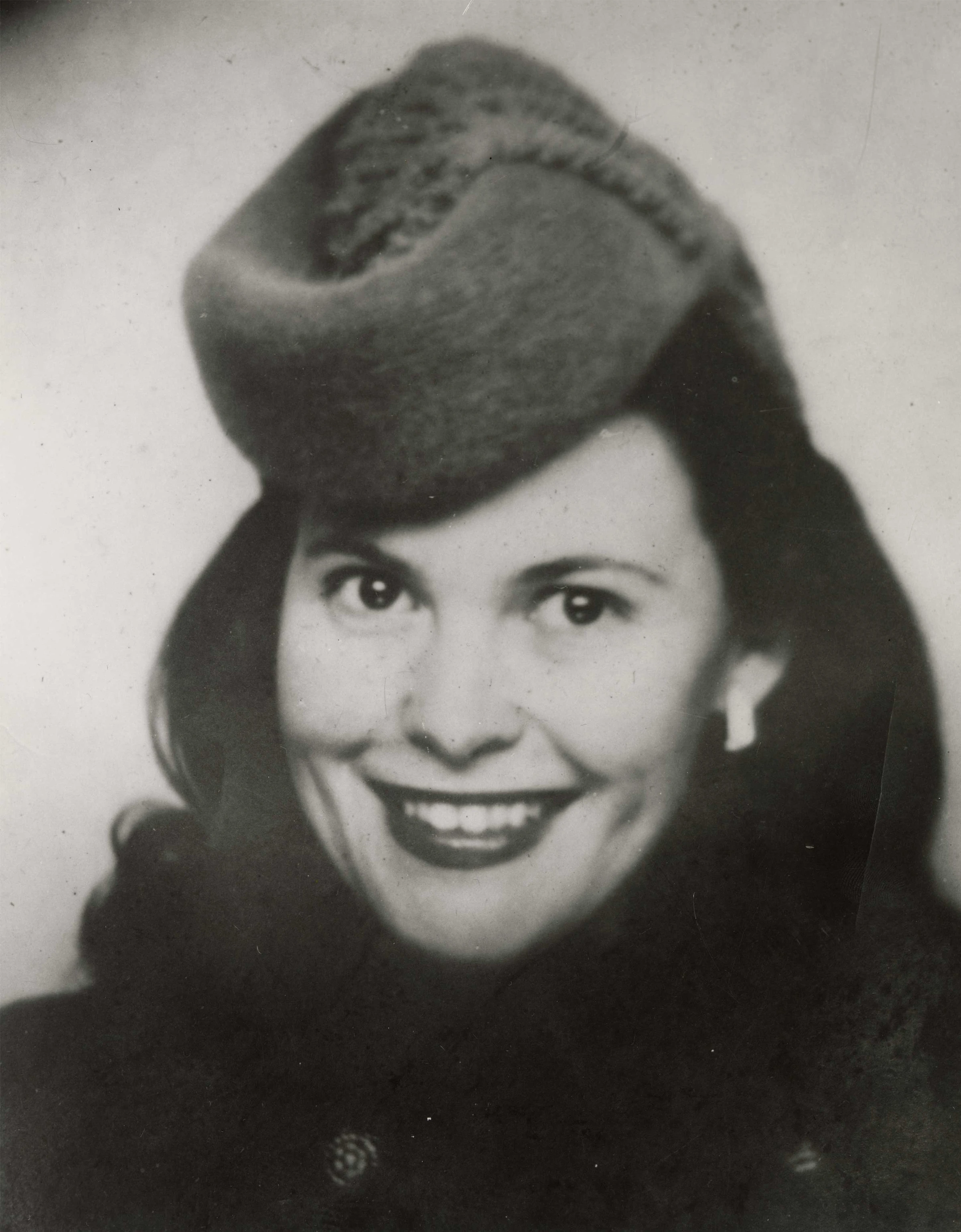 Close up of Ray Eames from the 1930s smiling and wearing a festive hat.