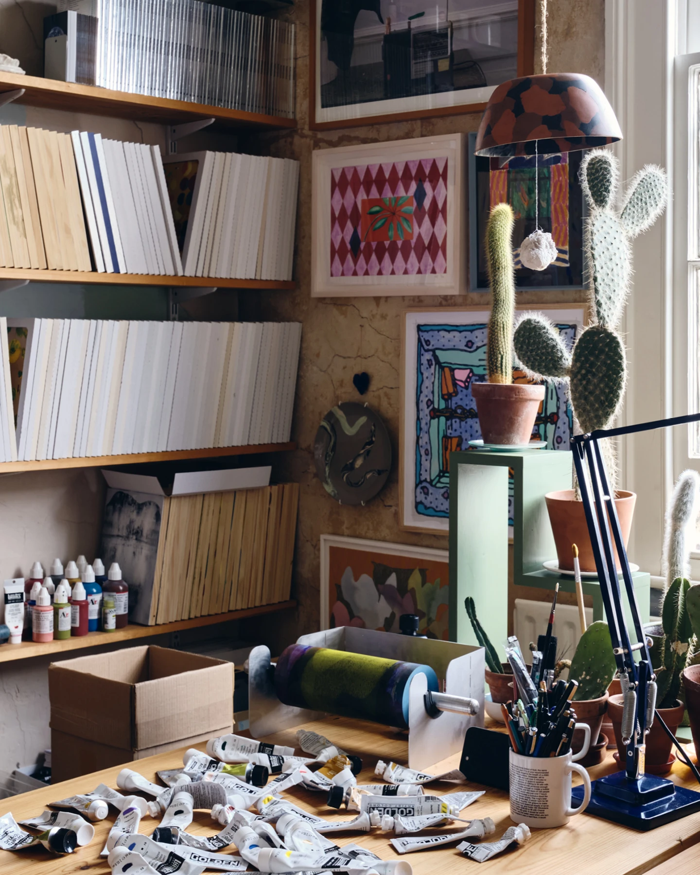 Artist Daniel Eatock’s London art studio work table covered with various paints and a rolling pin.