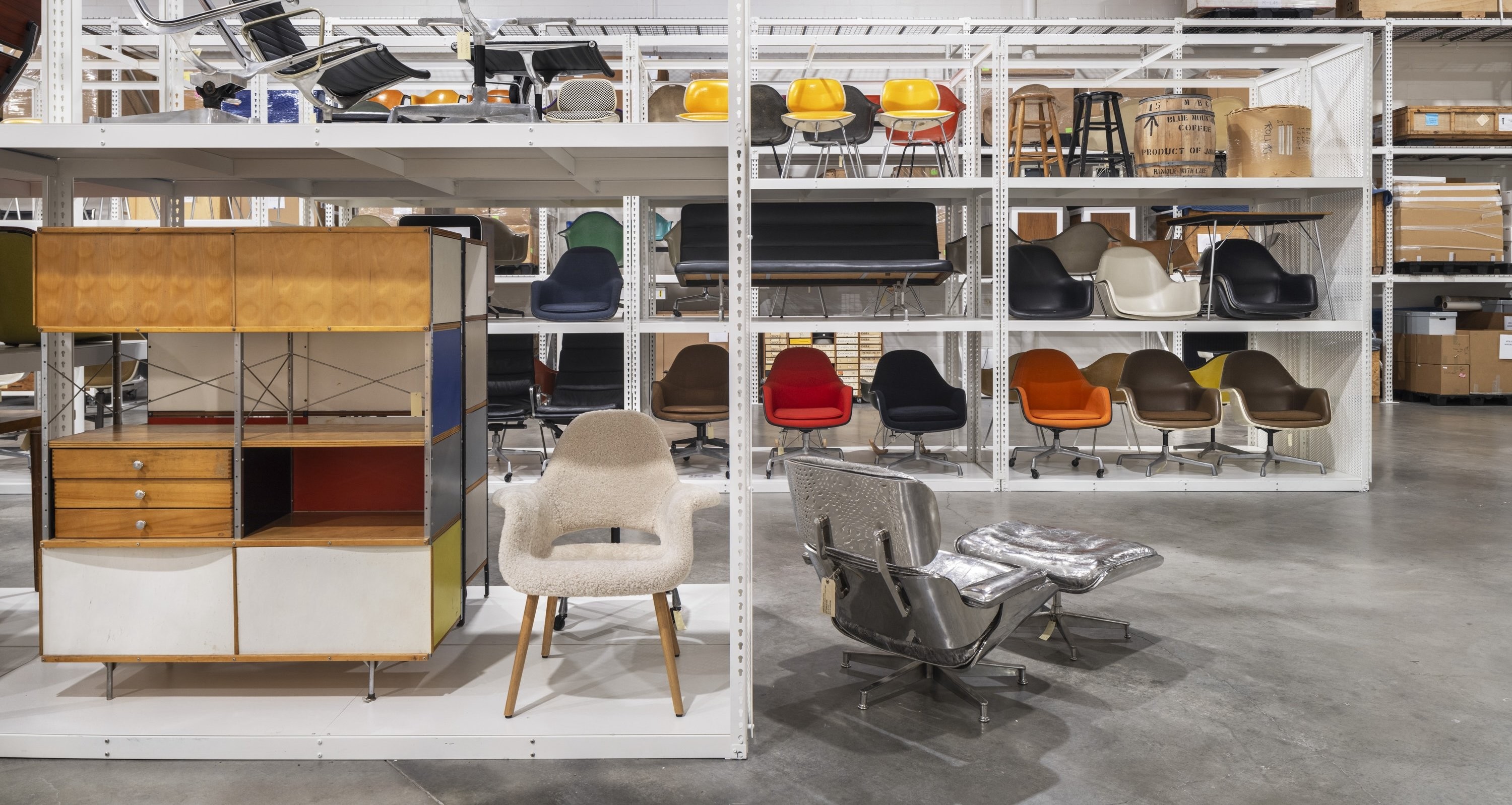 Tall white shelves at the Eames Archives filled with various Eames furniture and prototypes.