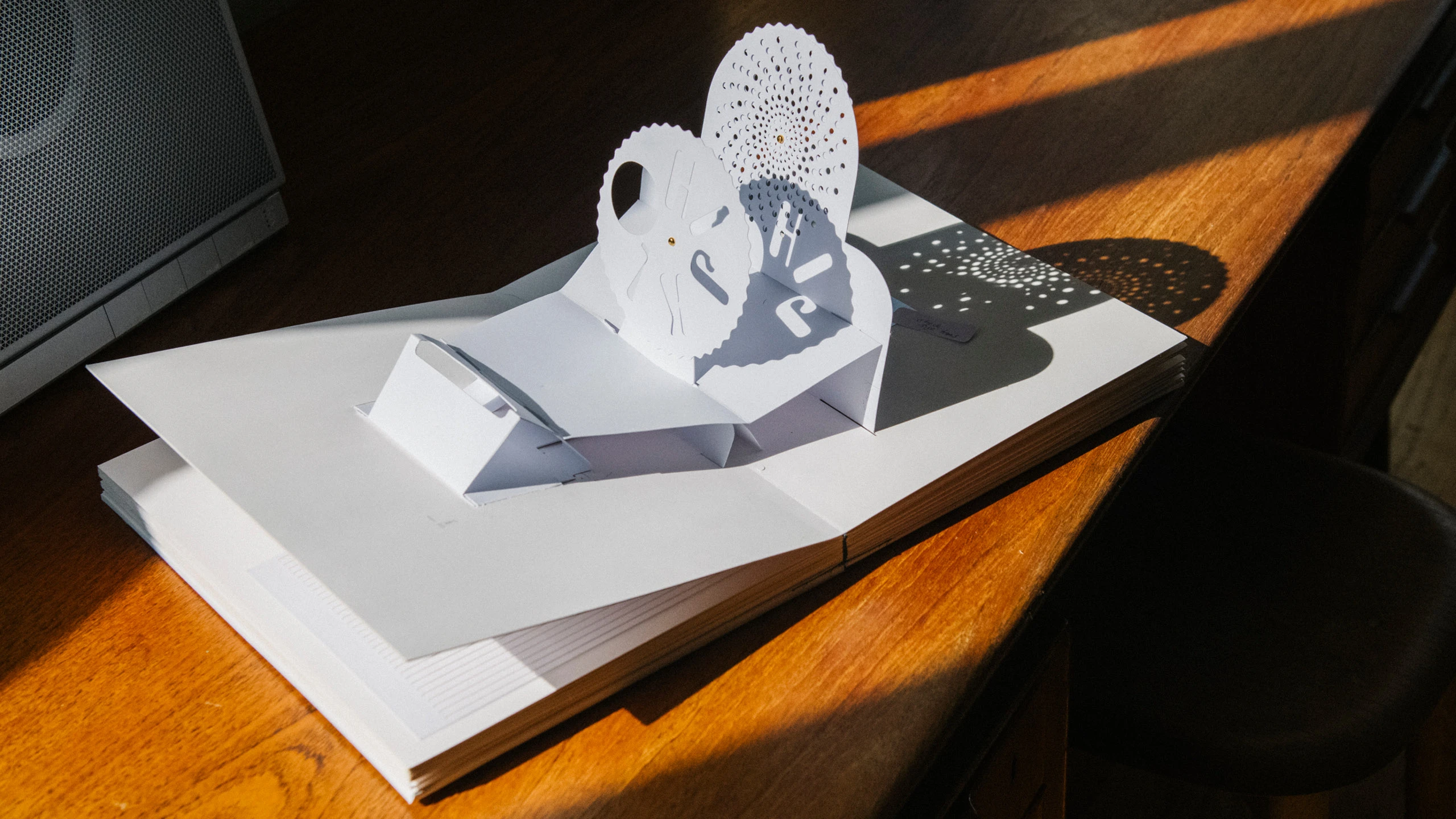 Pop-up book, “Alphabet in Motion”, open to a spread with several perforated disks and die cut letterforms.