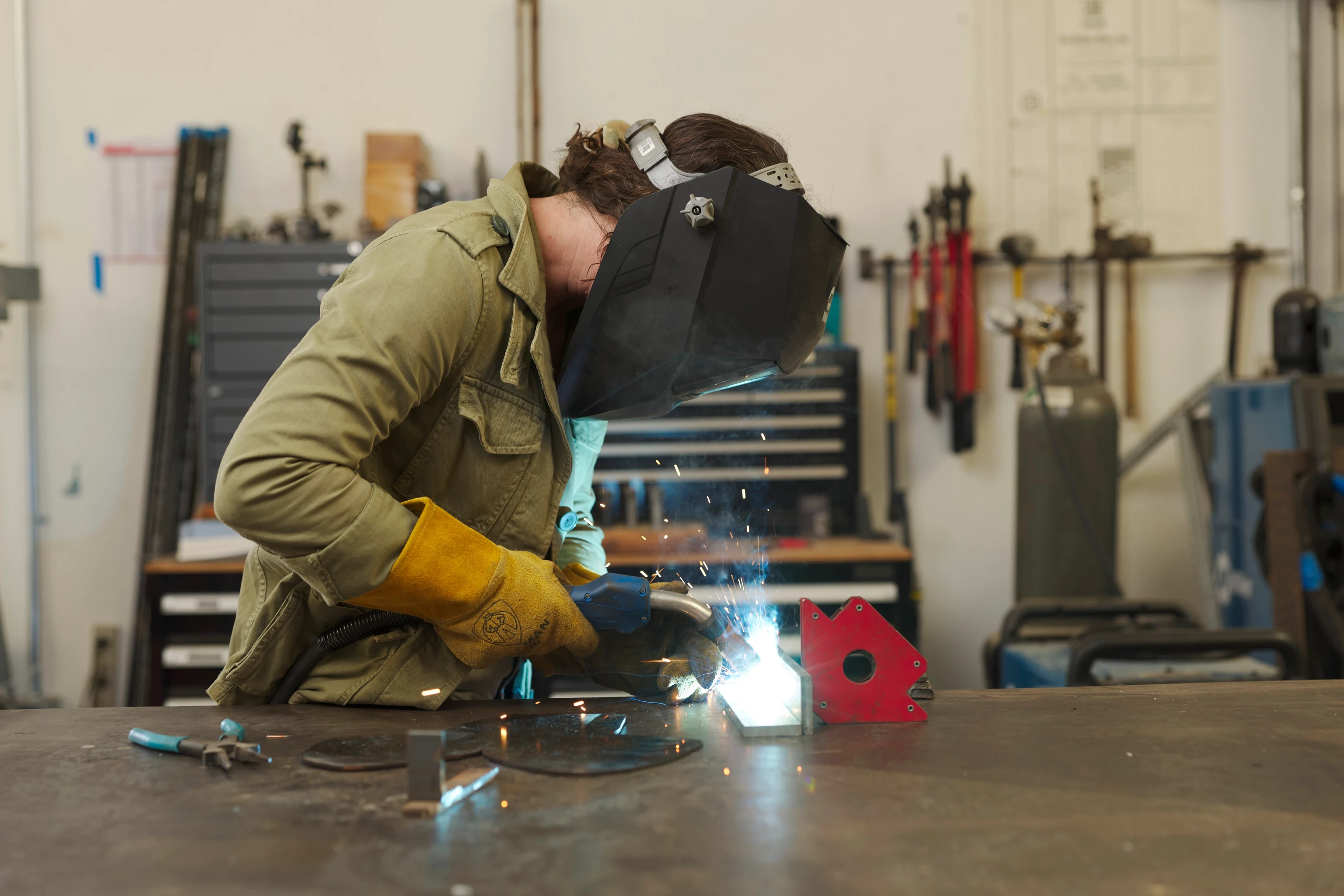 An artist in residency at the Eames Ranch Studios soldering a metal sculpture together.