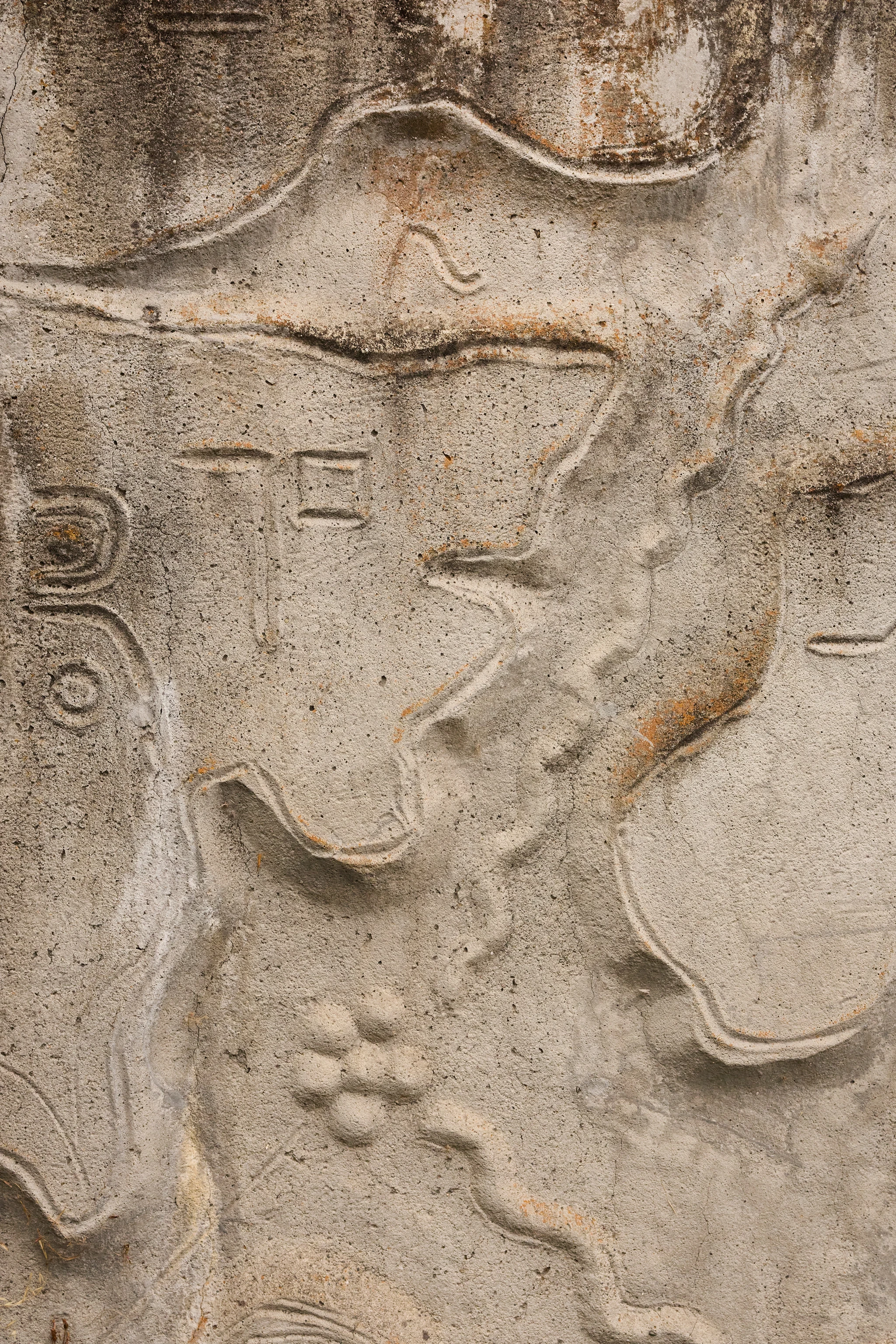 Close up from a carved concrete relief mural by artist Gurdon Woods featuring fluid abstract symbolic marks.