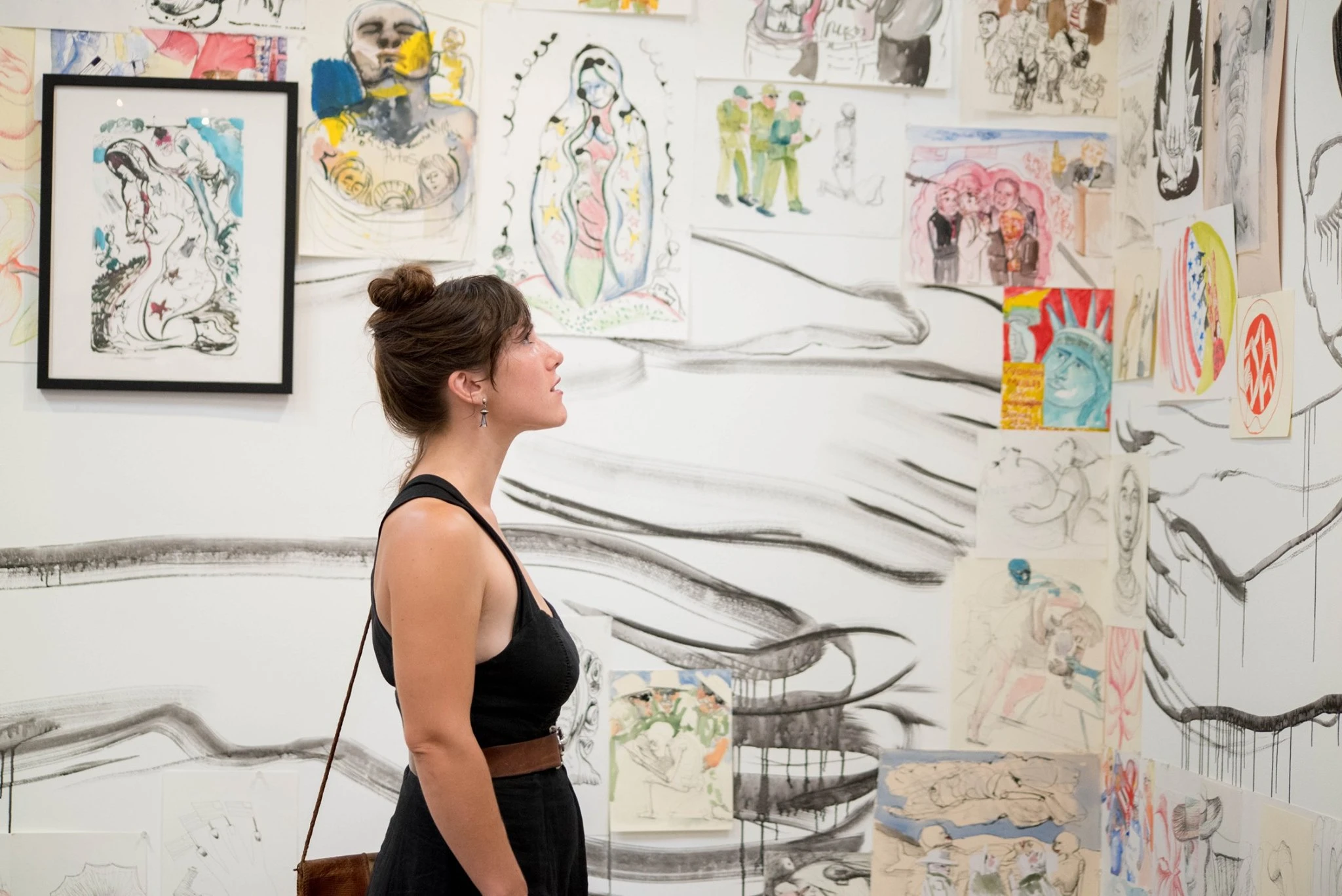 Visitor viewing a gallery installation at the Museum of Sonoma County, with walls covered in colorful drawings, paintings, and mixed-media artworks.