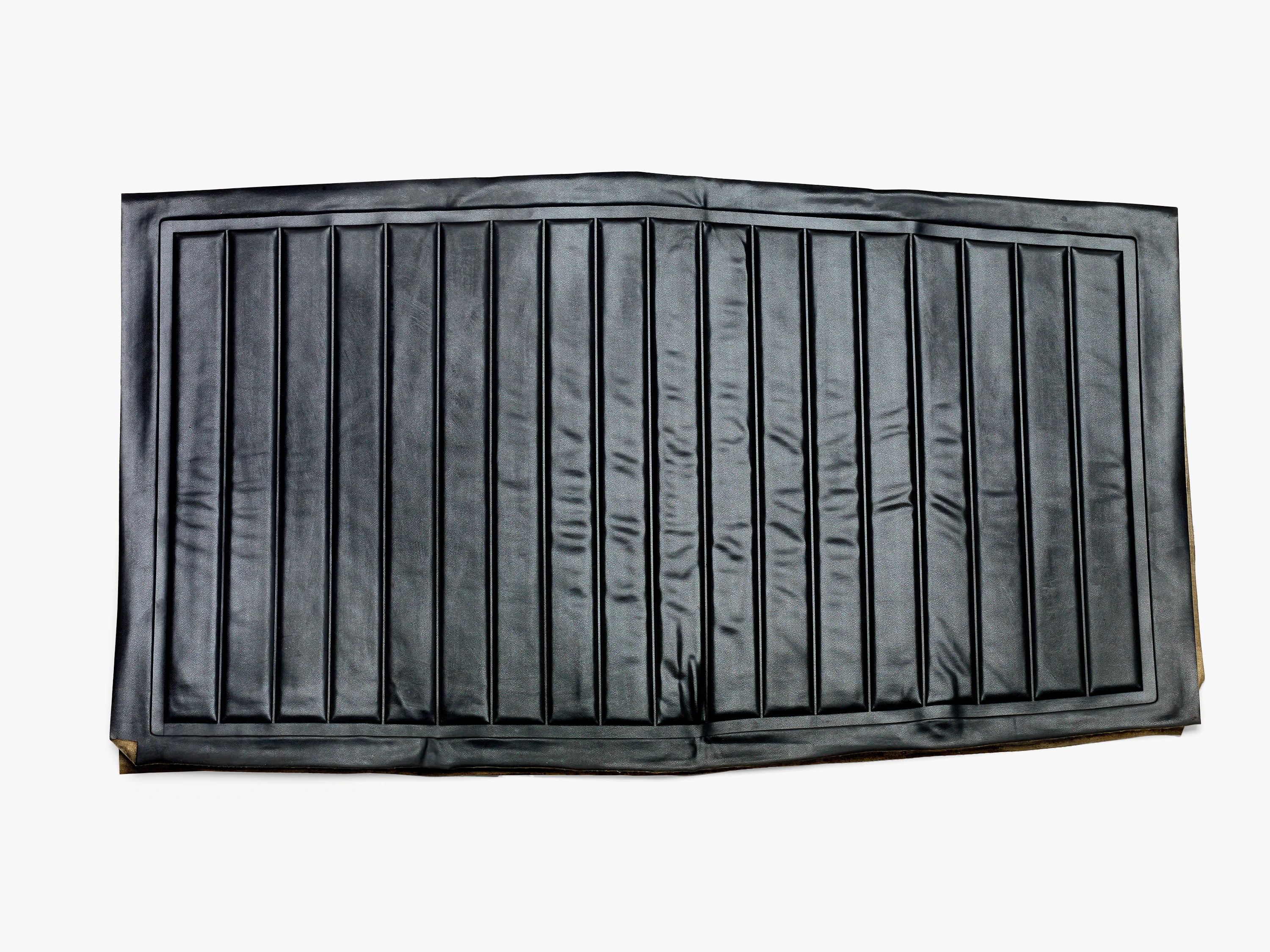Top down view of an Eames Aluminum Group seat cover prototype in black naugahyde with several heat-sealed horizontal grooves.