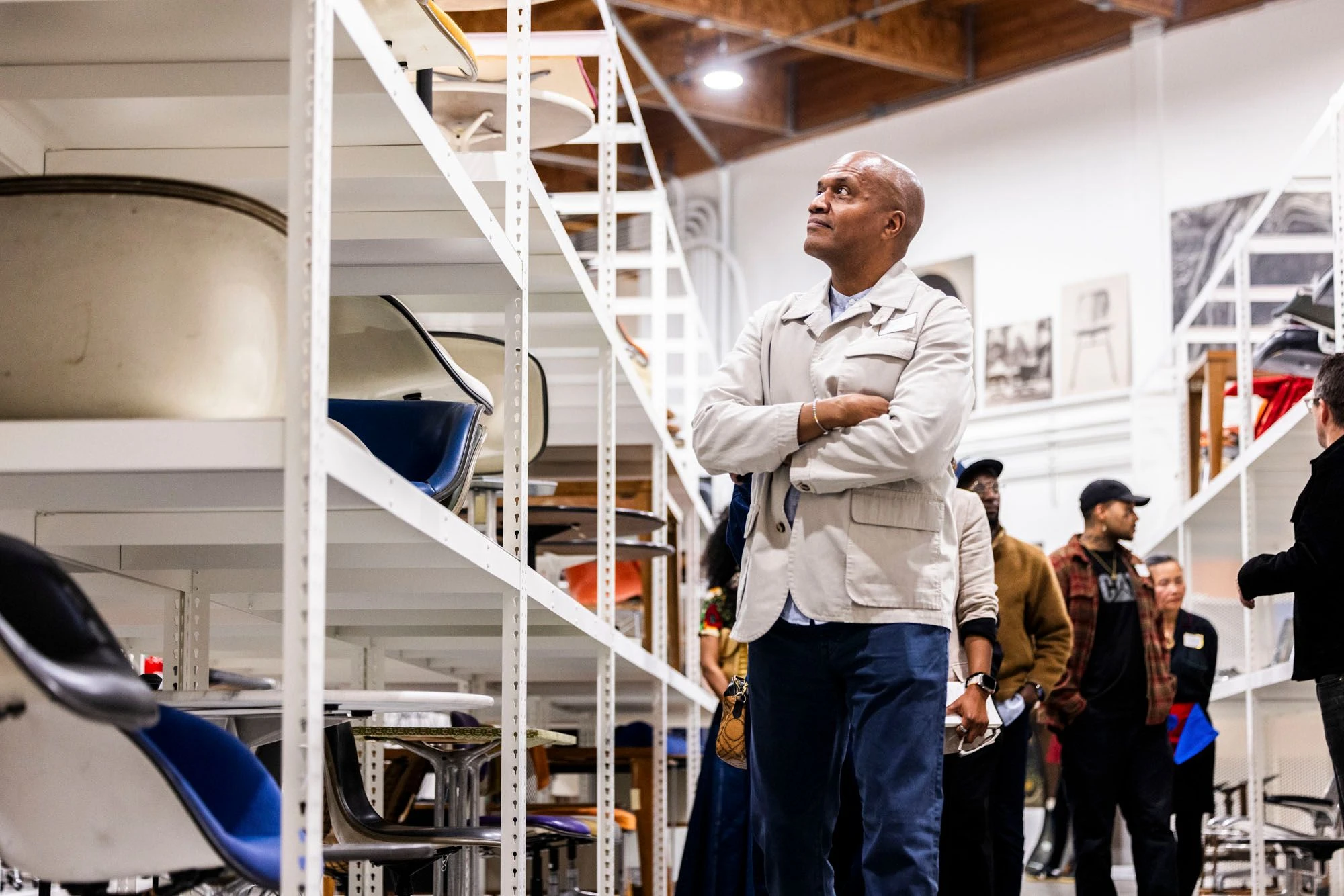 Inside the Eames Archives are many shelves with Eames furniture designs and guests attending a tour.