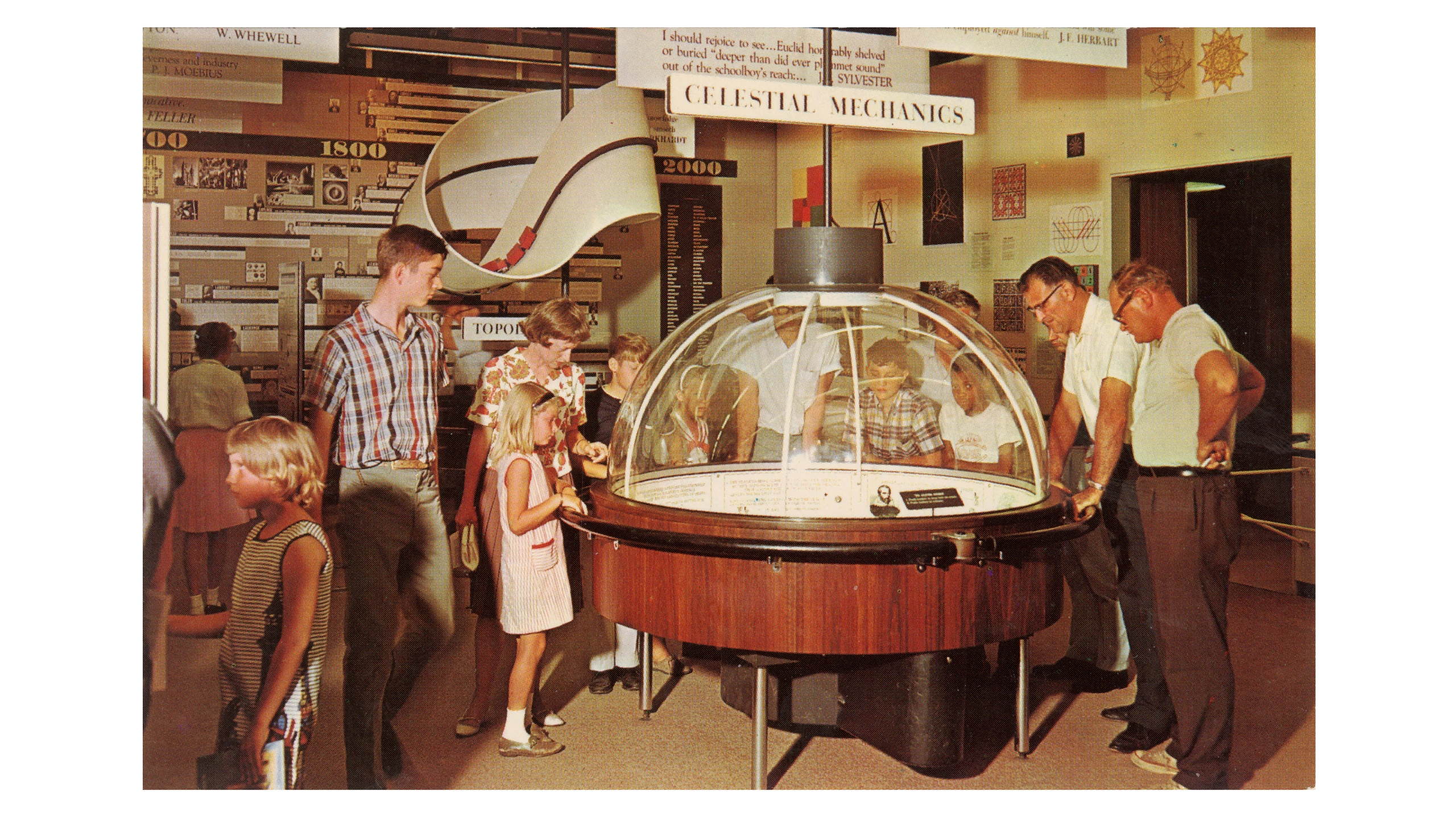 Several people gathered around the dome-shaped Celestial Mechanics installation at the Eames Mathematica exhibition.