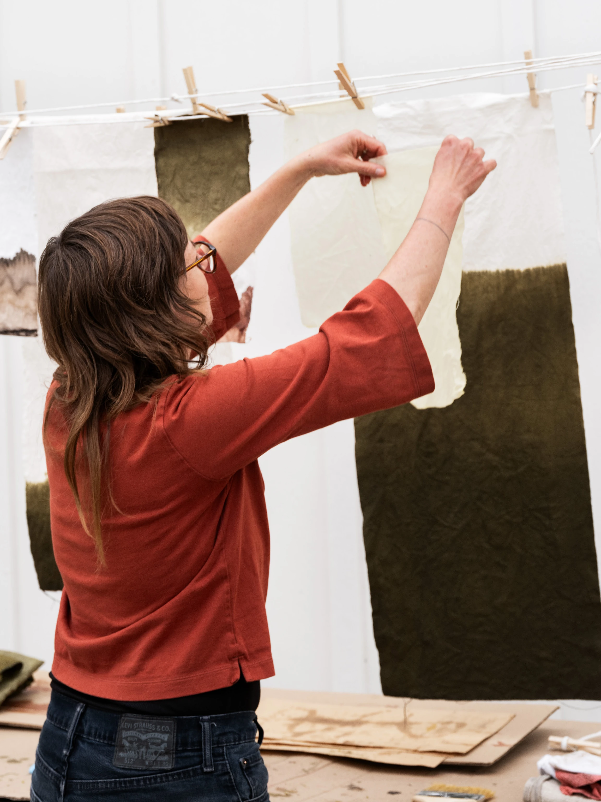 An artist in residency at the Eames Ranch Studios hangs dyed papers to dry on a clothesline.