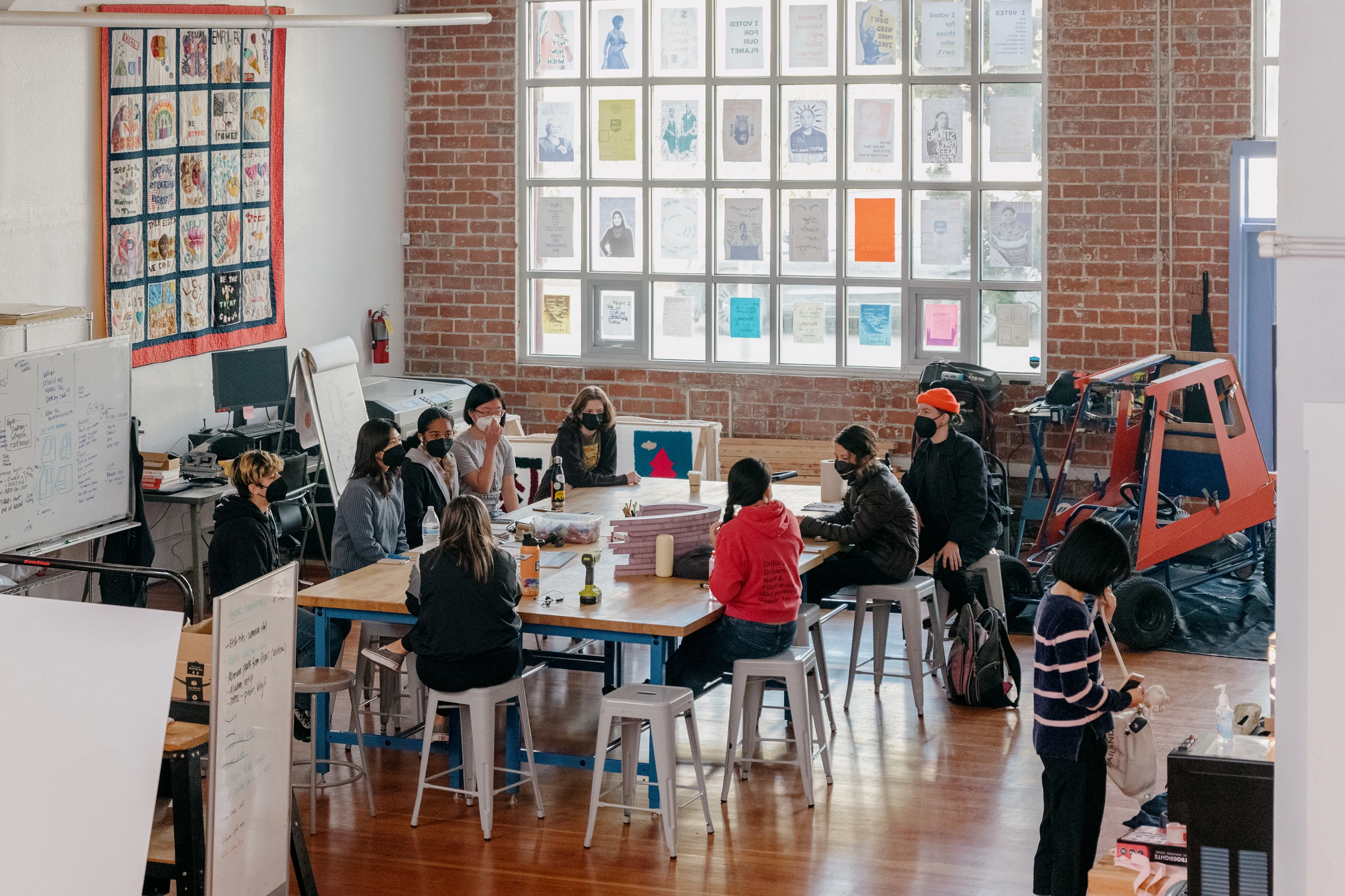Girls Garage, a design/build workshop in Berkeley California with Emily Pilloton-Lam,  founder and executive director sitting among her students in the workshop.