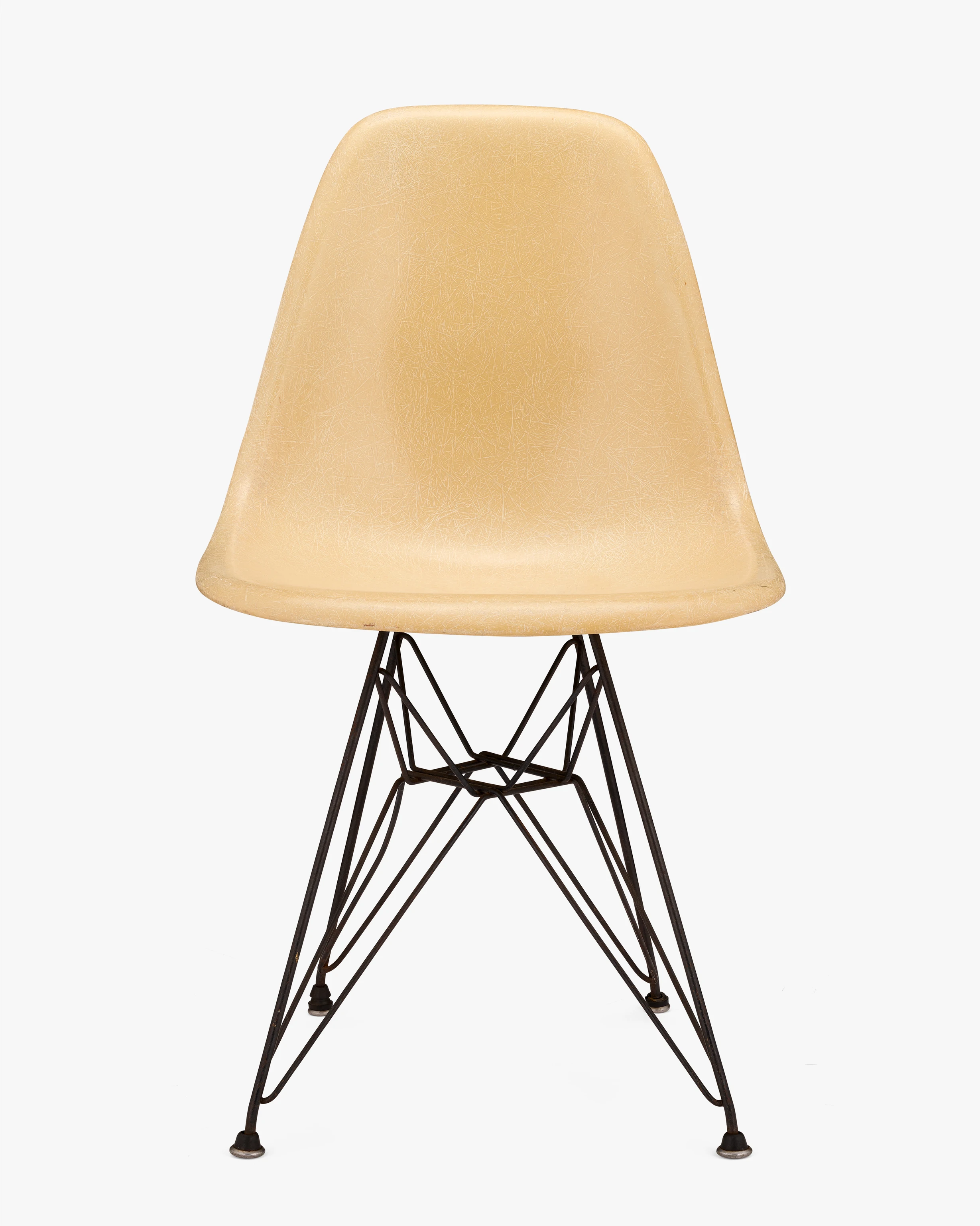 Front view of an early Eames DSR chair. The fiberglass shell is a light muted yellow and the base is made of steel.