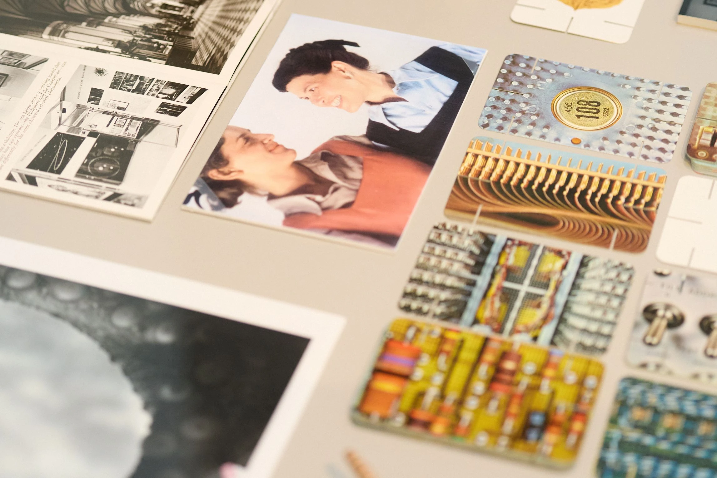 Close up of artifacts from the Eames Archives, including a photograph of Ray Eames with Charles’s daughter, Lucia, and cards from the House of Cards deck.