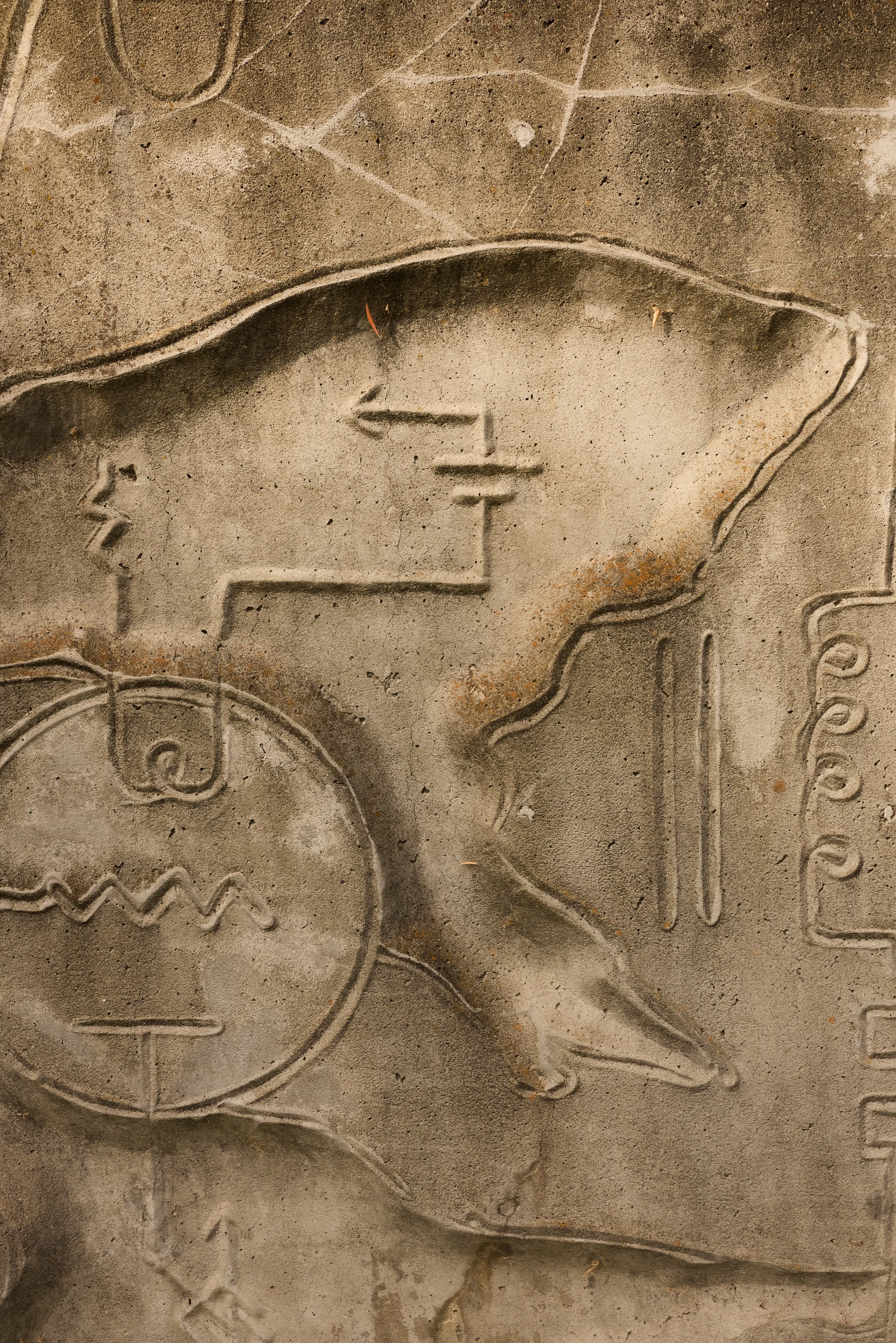 Close up from a carved concrete relief mural by artist Gurdon Woods featuring geometric symbolic marks.
