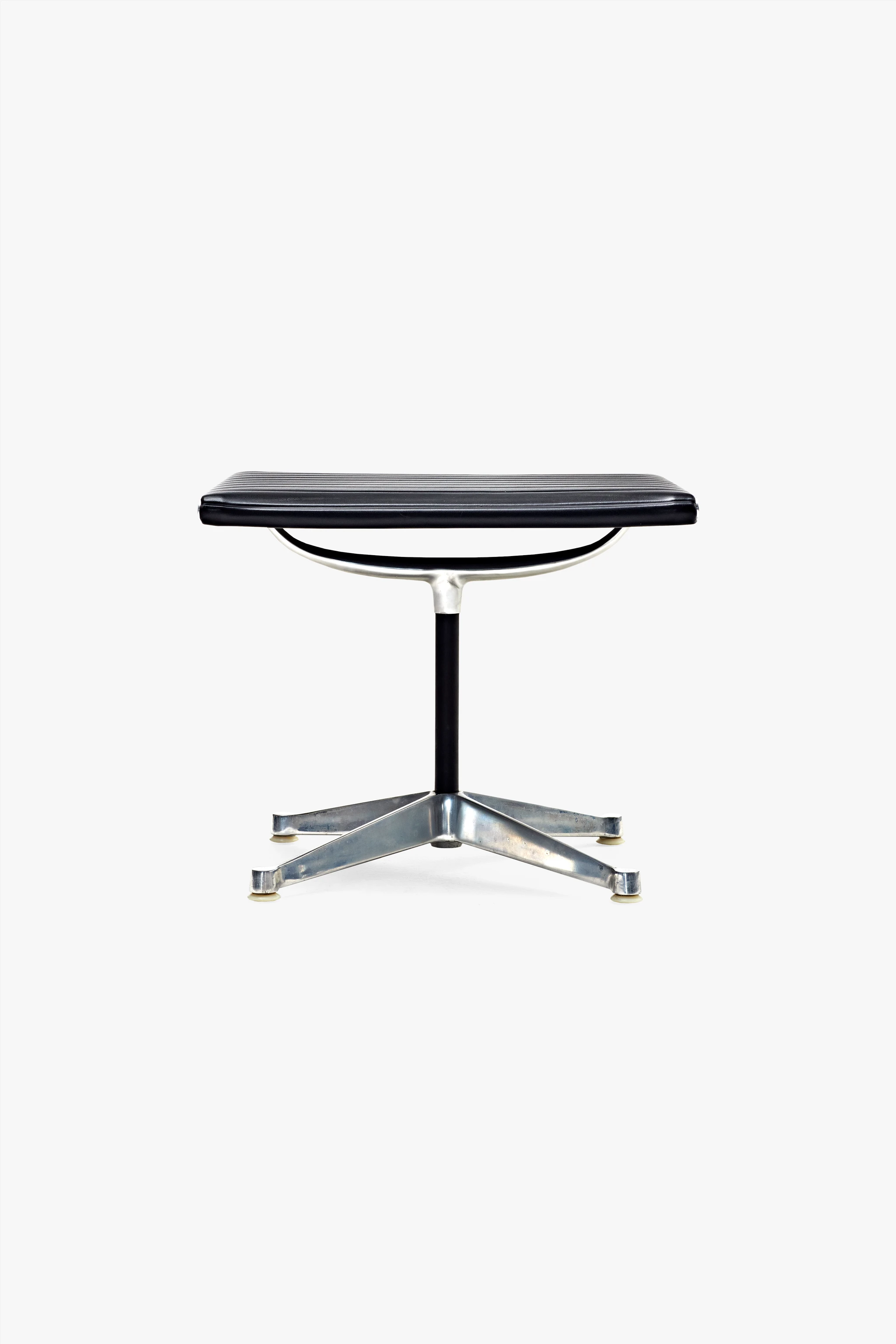 Front view of the Eames Aluminum Group 685 Ottoman, with black Naugahyde upholstery and a steel base.