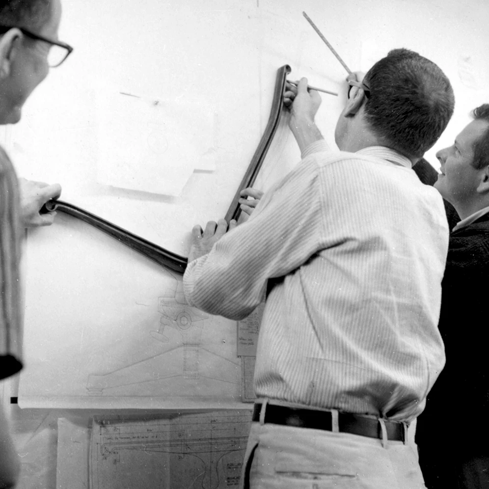 Charles Eames and staff trace the outline of an Eames Aluminum Group side member for scale drawing. Image © Eames Office, LLC